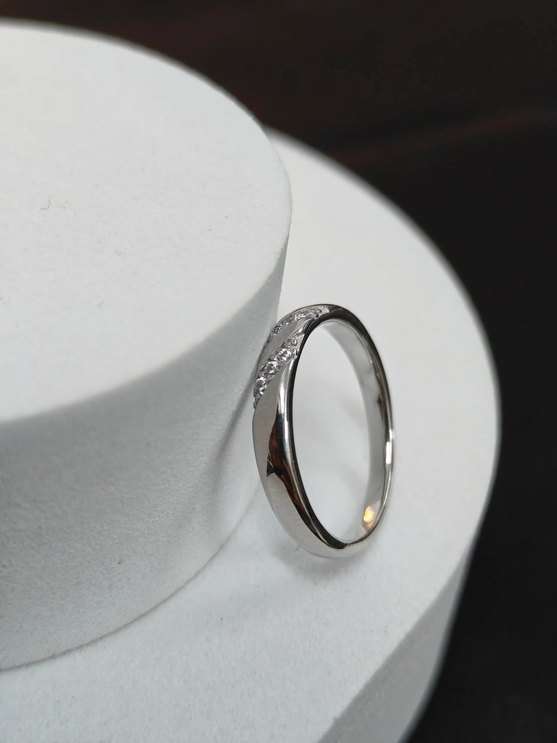 Silver ring on a white surface with a dark background