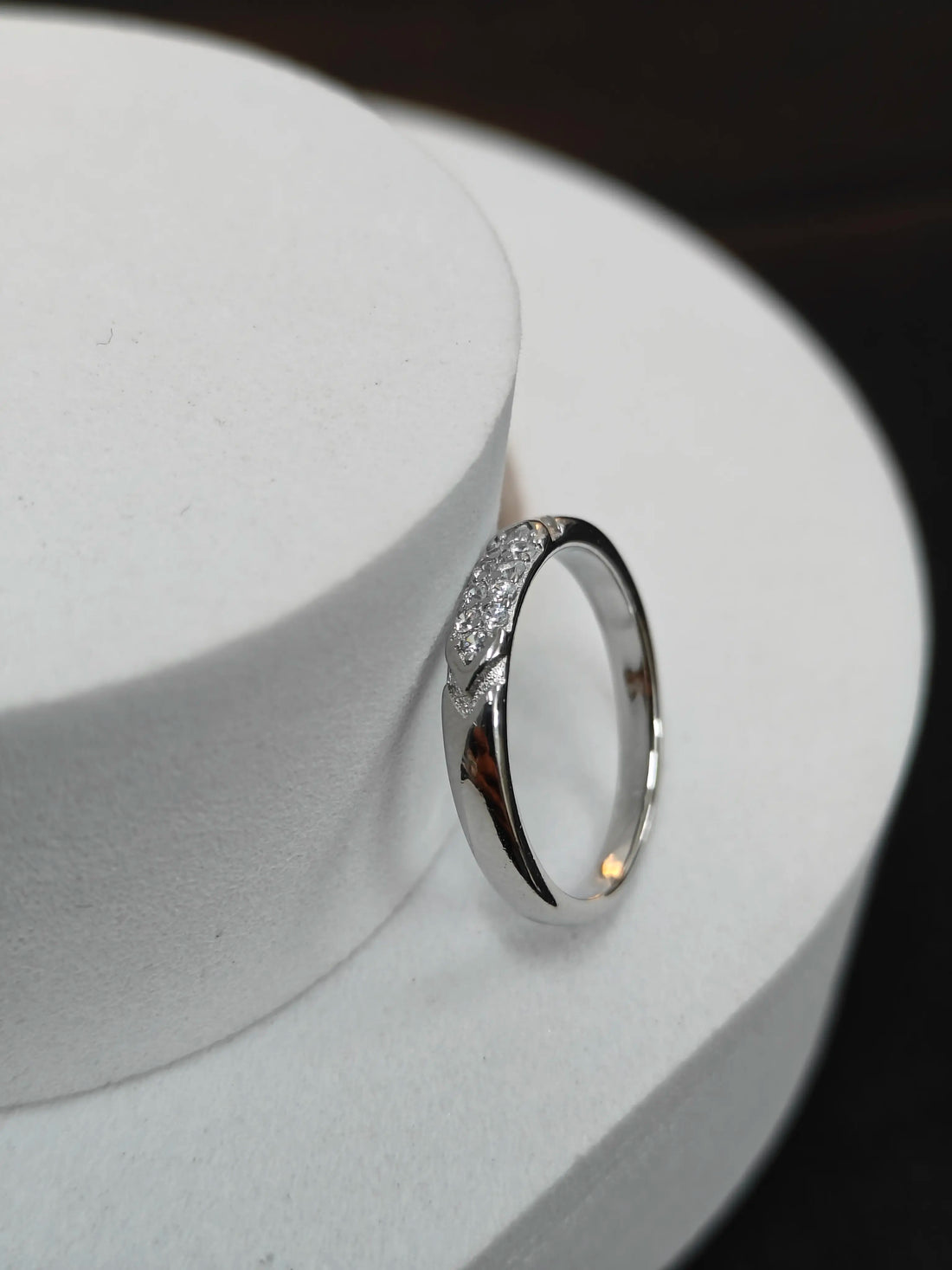Silver ring with small diamonds on a white stand