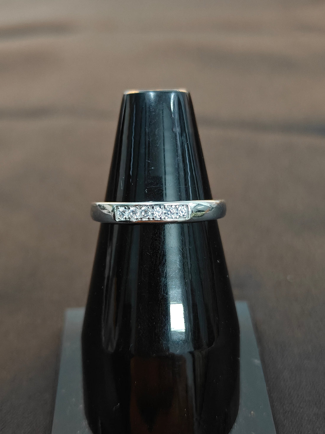 Silver ring on a black cylindrical object with a brown background