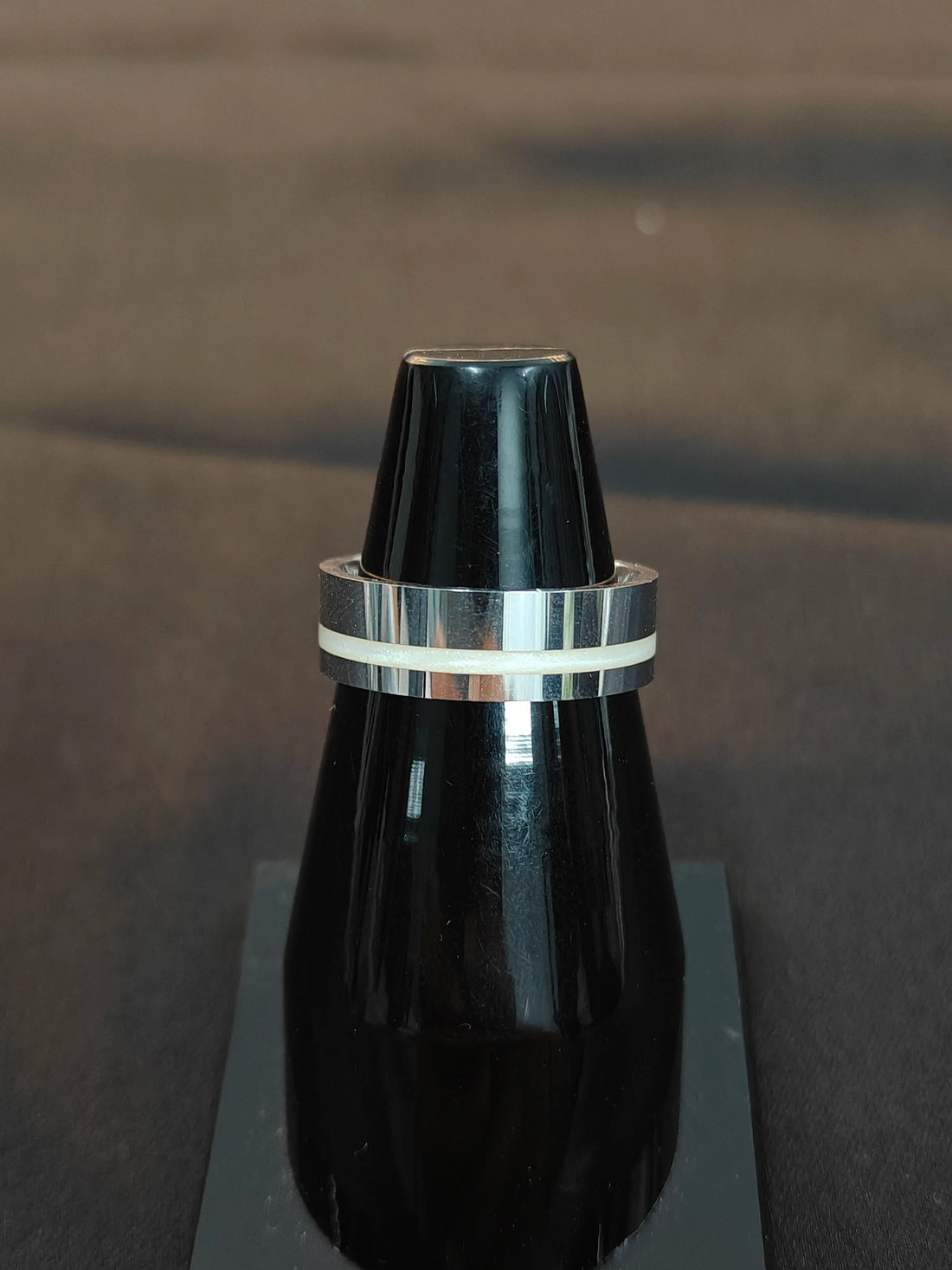 Black object with a silver band on a reflective surface