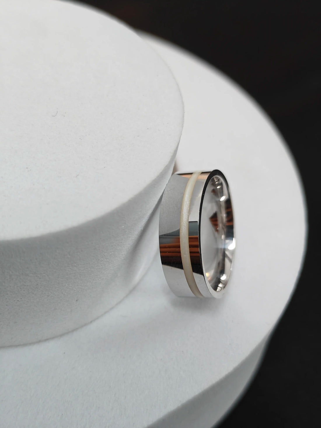 Silver ring with a wooden inlay on a white surface