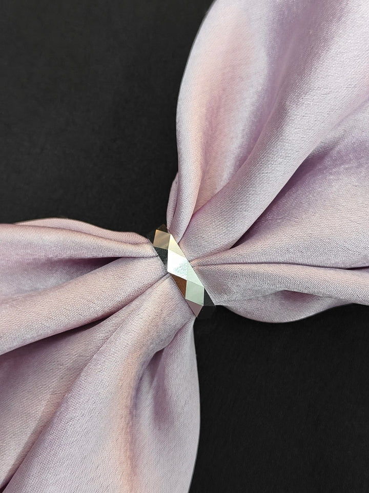 Close-up of a knotted lavender fabric with a metallic ring on a black background