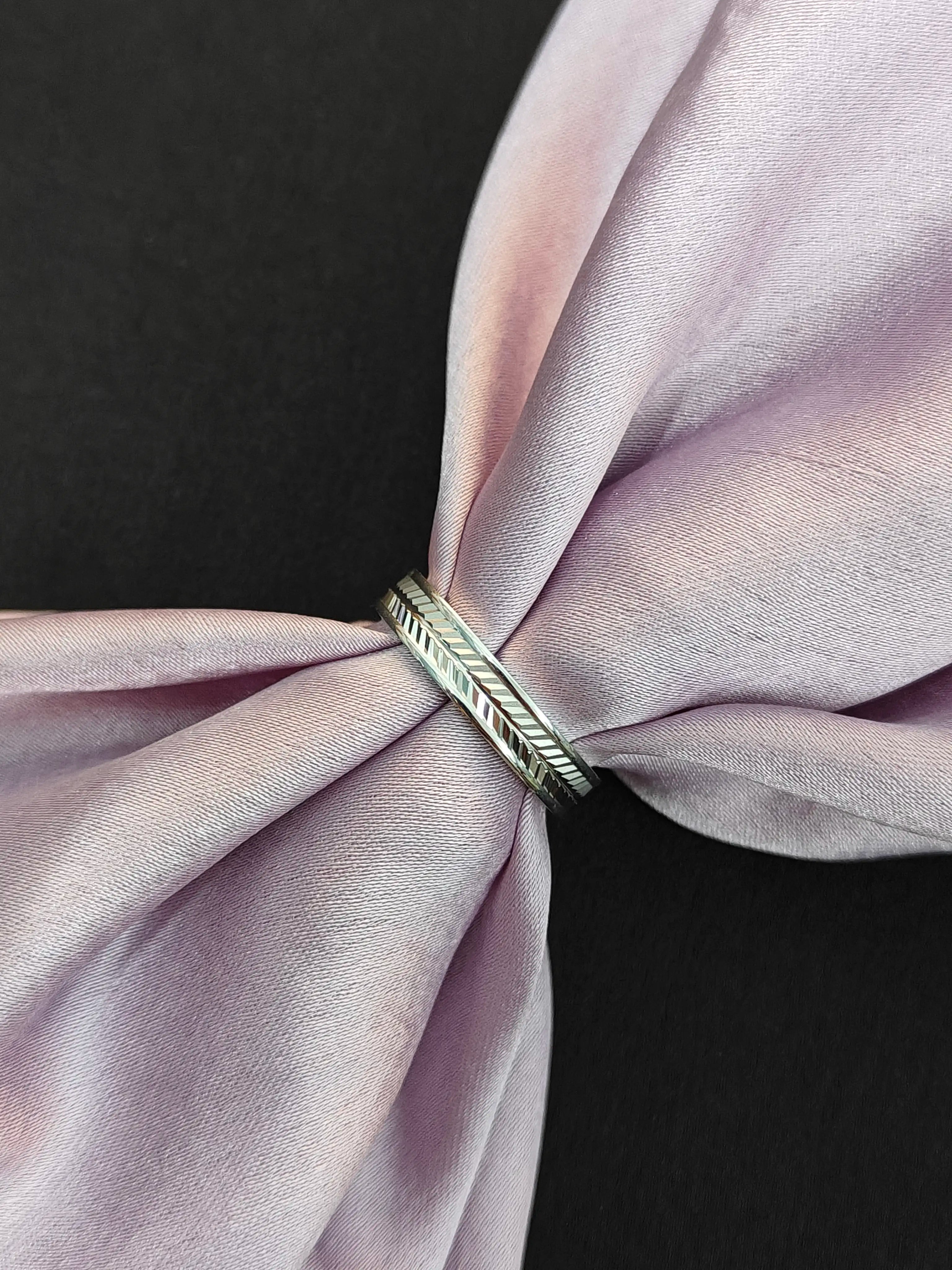 Silver ring with a feather design on a pink fabric background