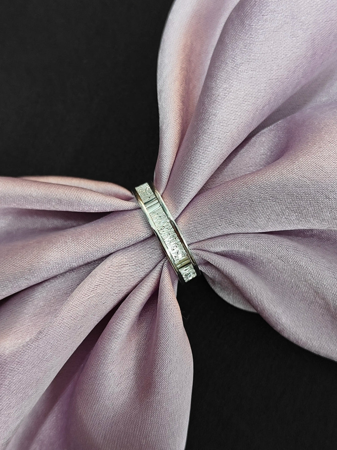 Silver ring with a diamond on a pink fabric background