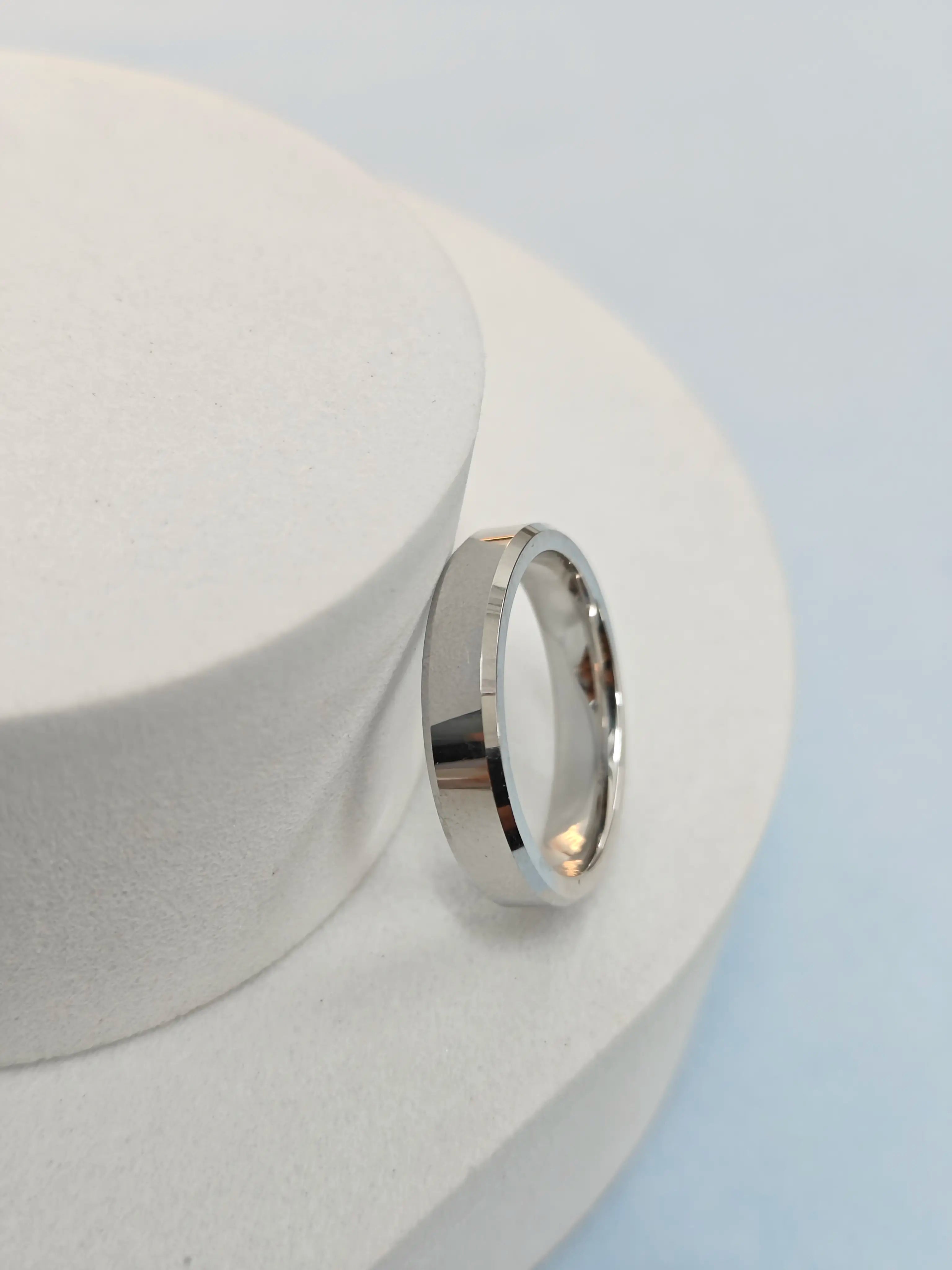 Silver ring on a white cylindrical object with a light blue background