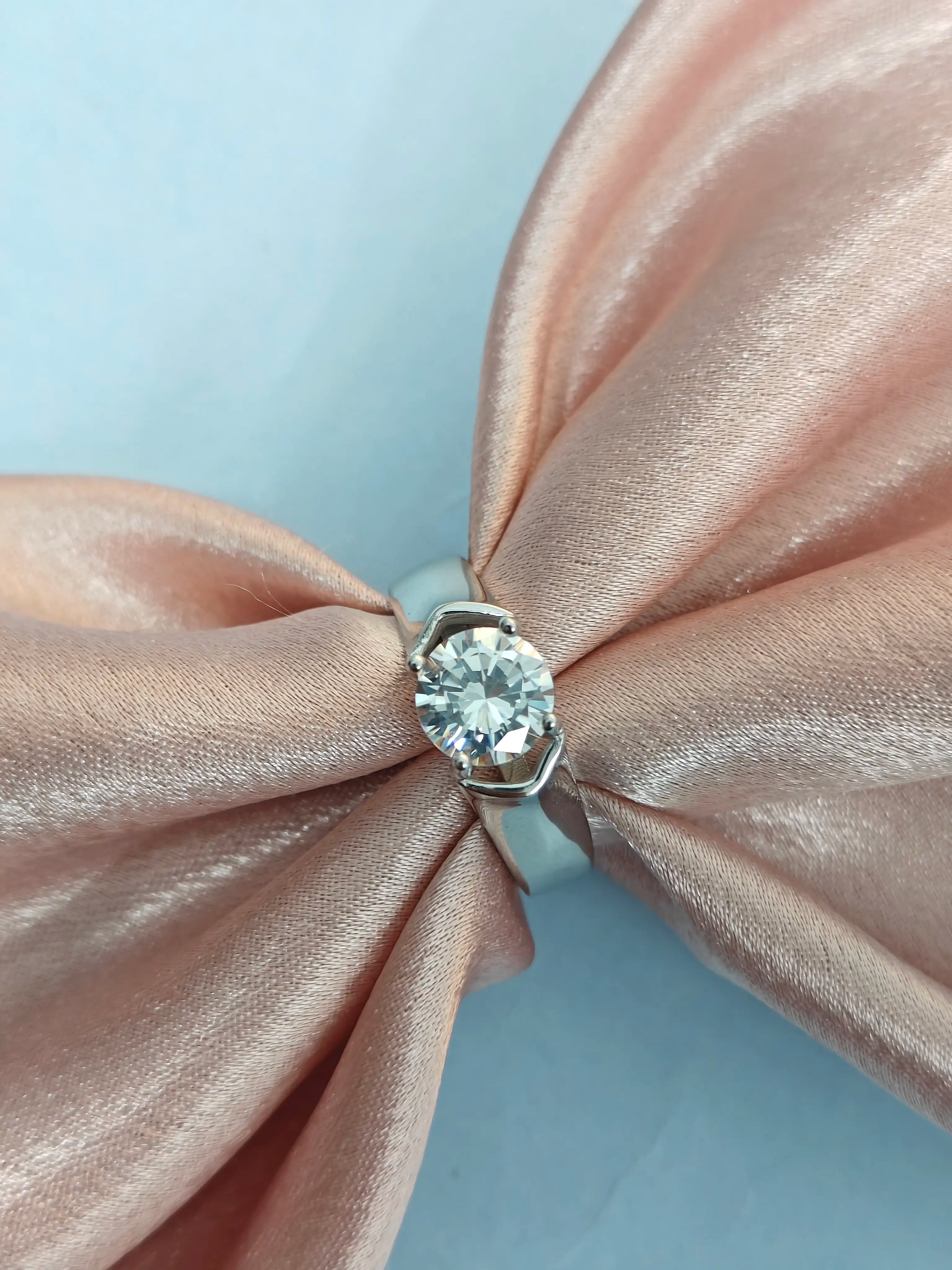 Diamond ring on a pink satin bow with a light blue background