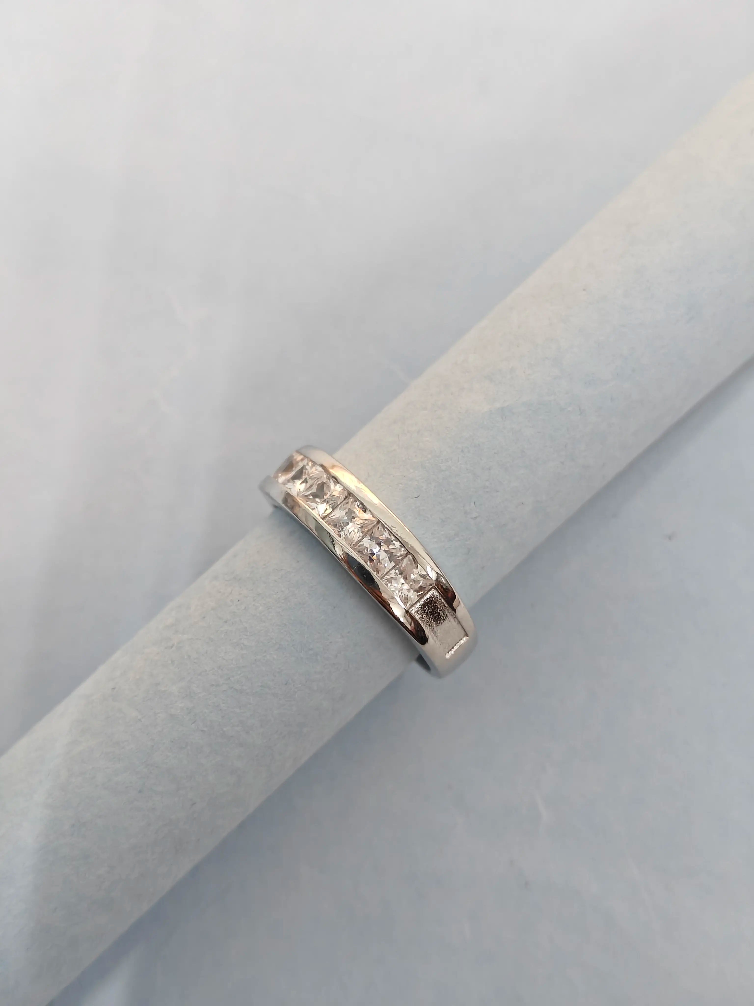 Silver ring with small diamonds on a light gray background
