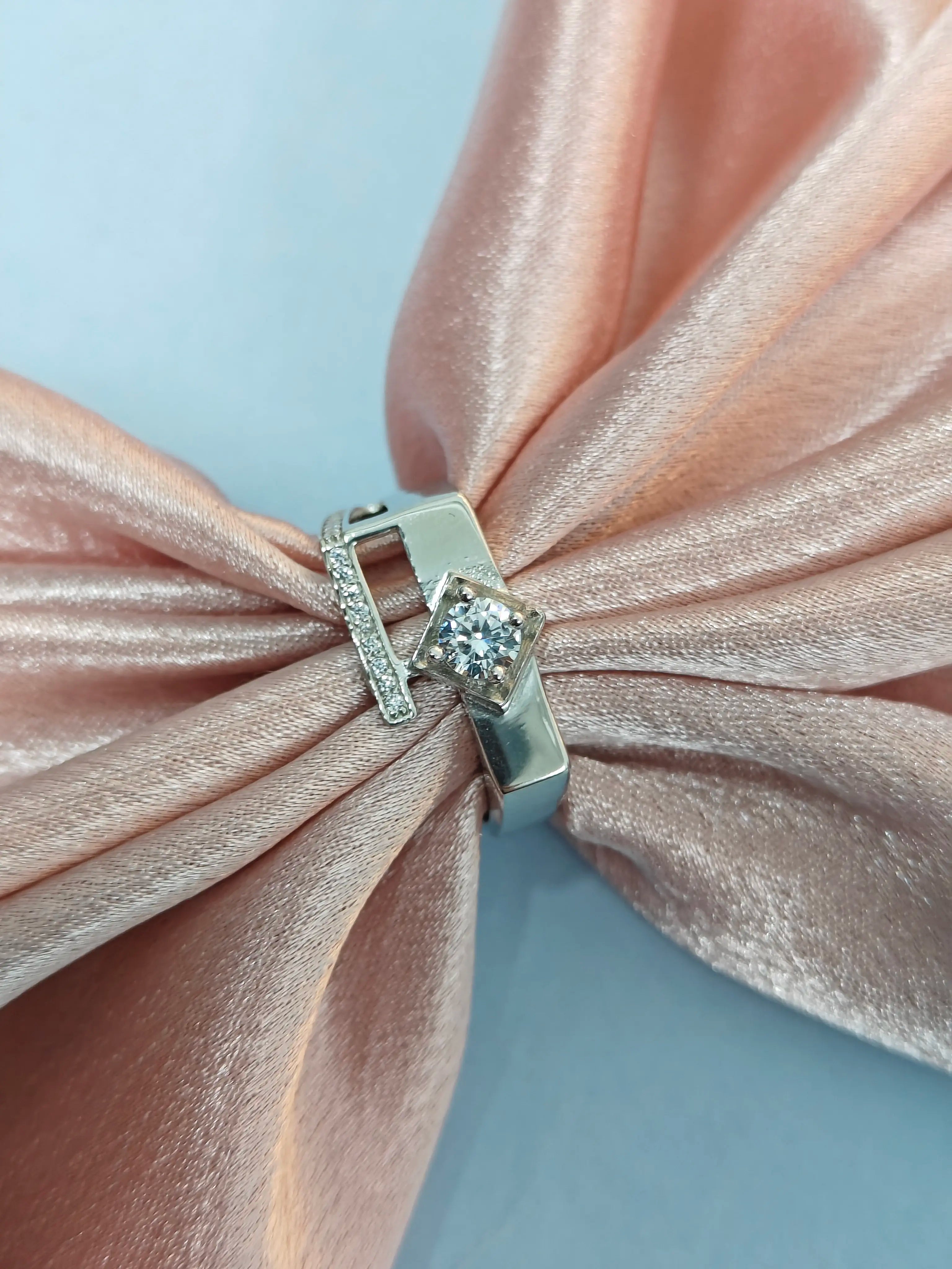 Silver earring with a diamond on a pink bow background