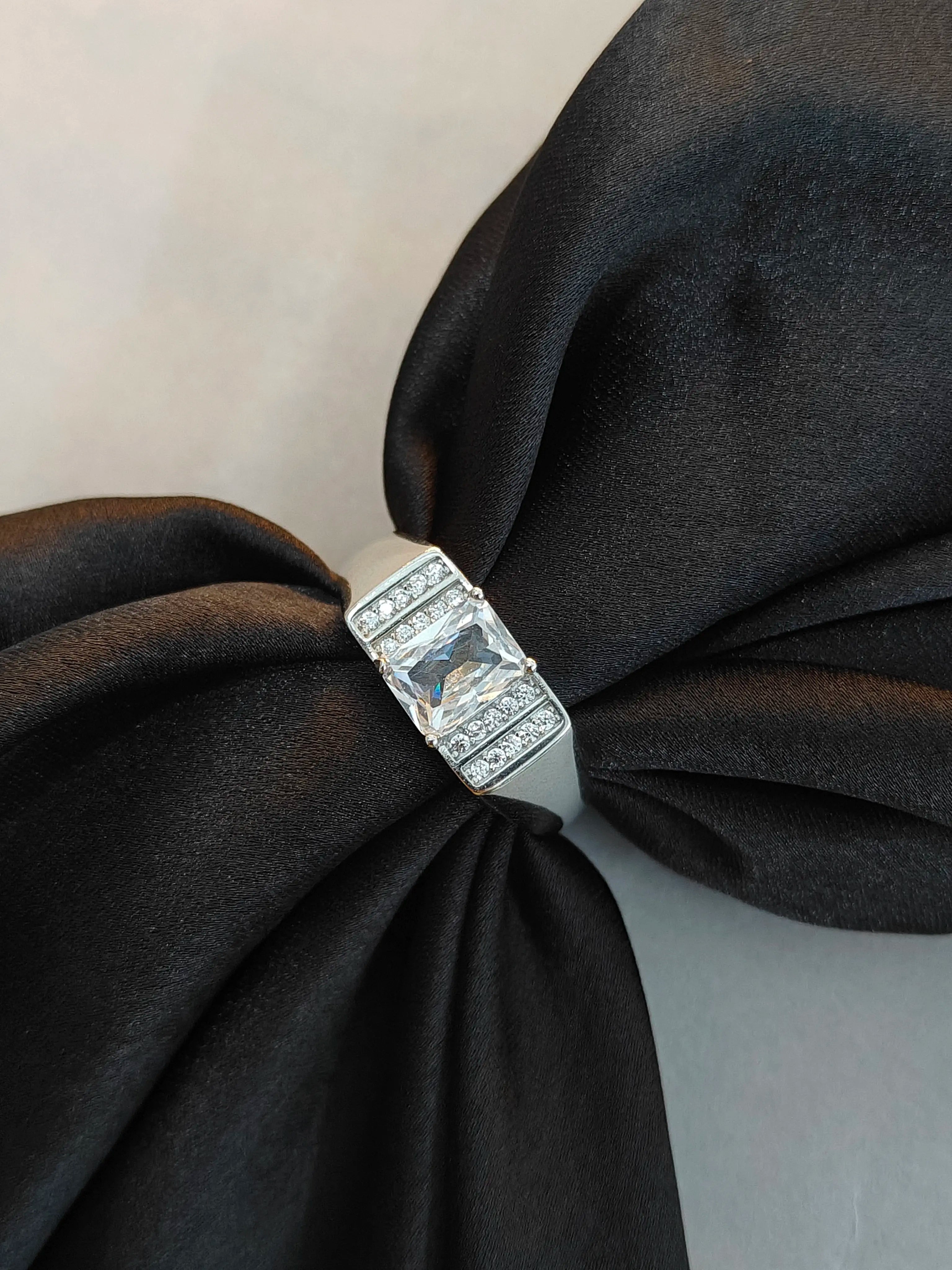 Diamond ring on a black fabric bow against a neutral background