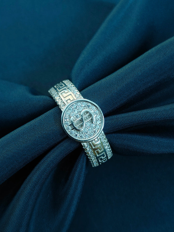 Silver ring with a circular design on a navy blue fabric background