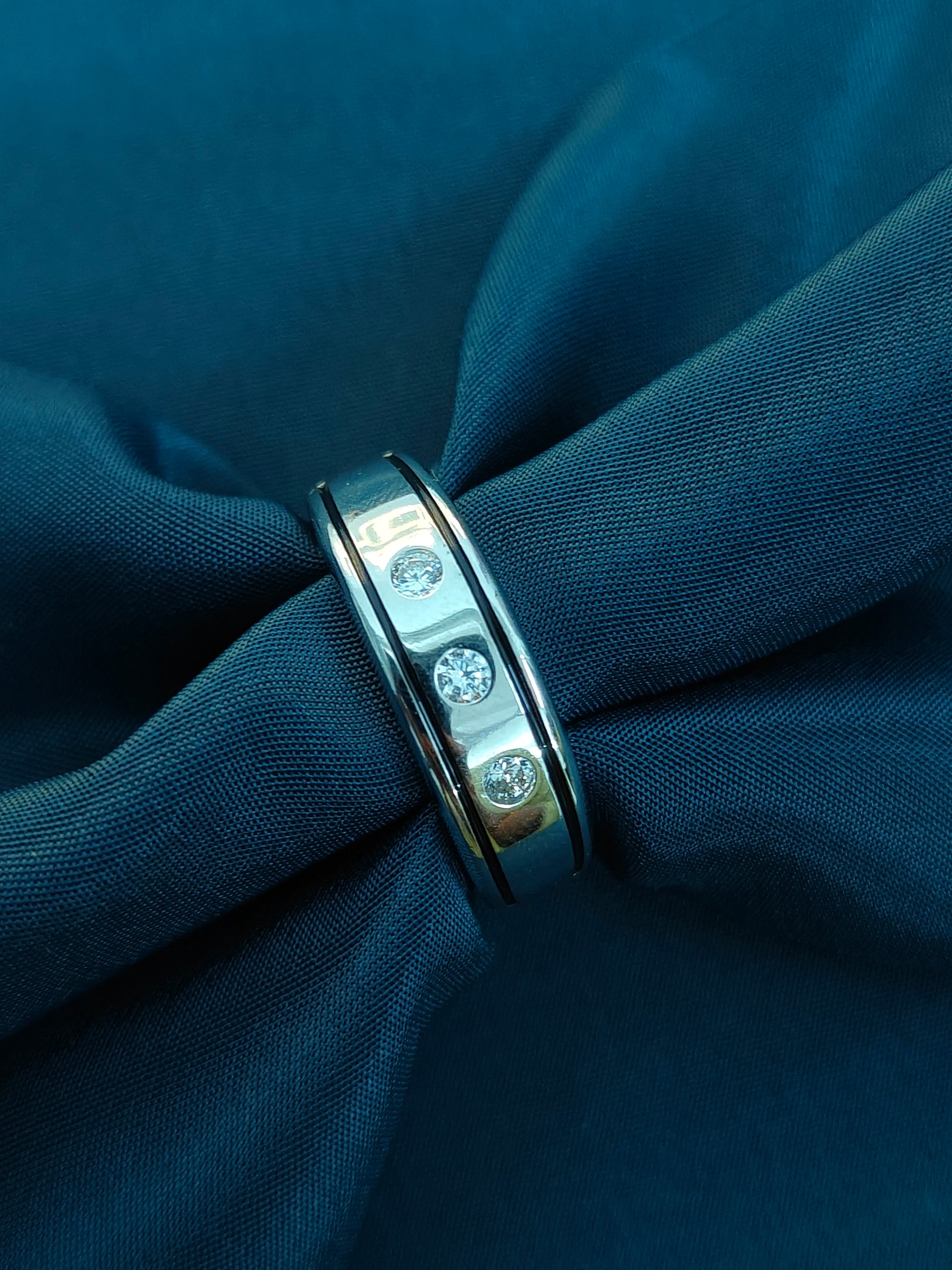 Silver ring with embedded stones on a blue fabric background