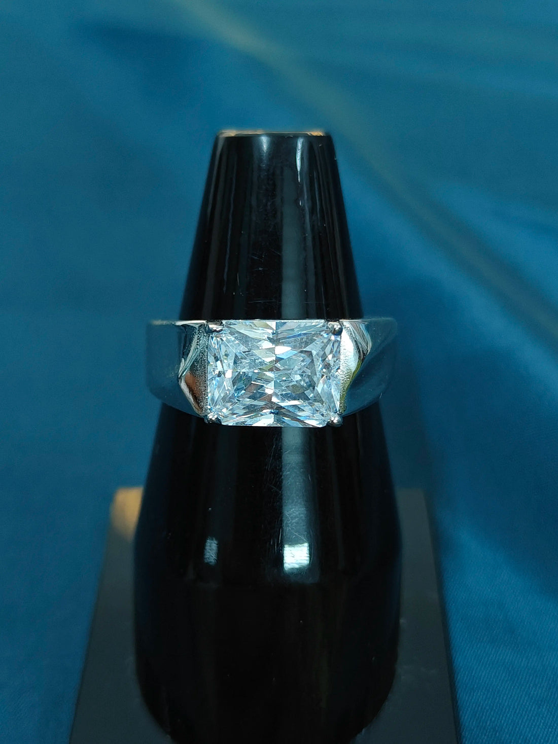 Diamond ring on a black stand against a blue background