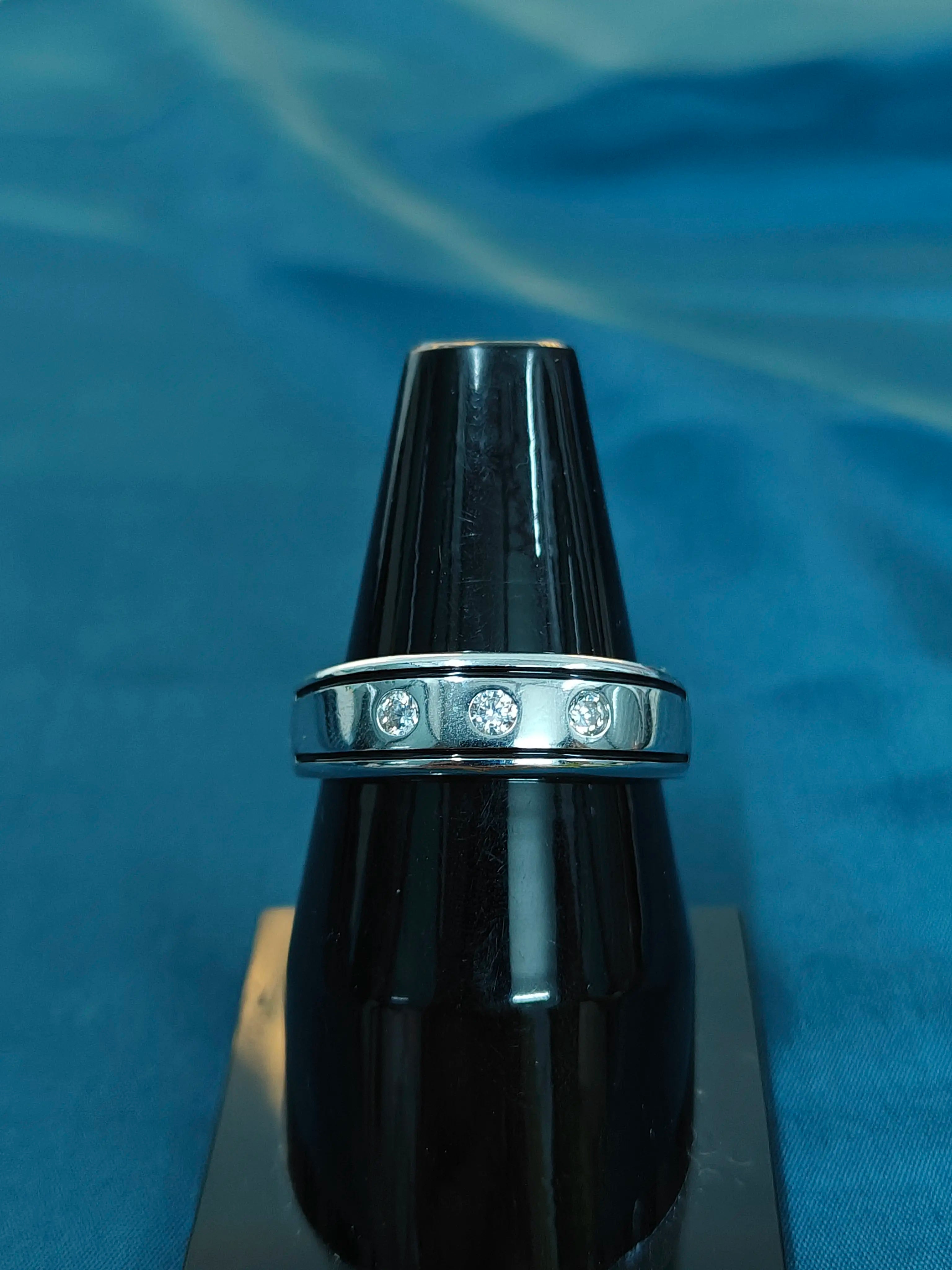 Black ring with a silver band featuring diamonds on a blue background