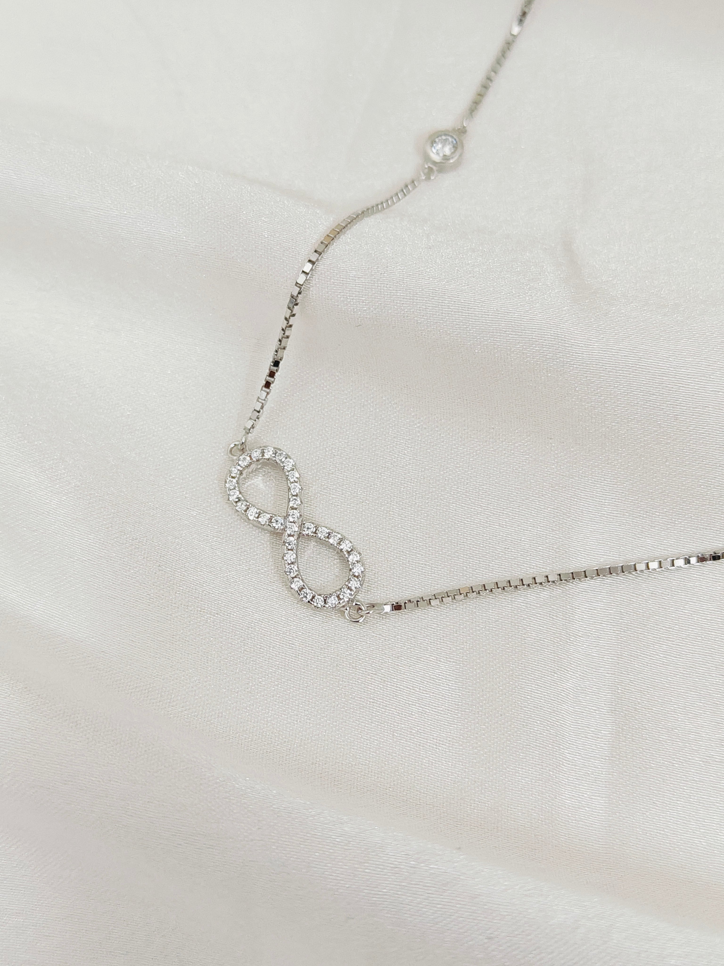 Silver infinity necklace on a light gray background