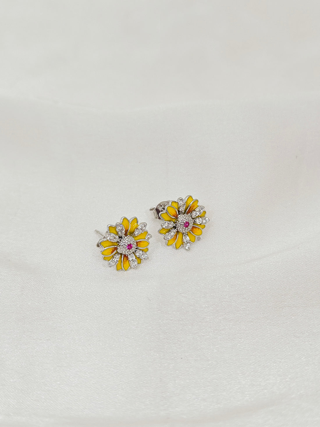 Pair of yellow flower-shaped earrings on a light gray background