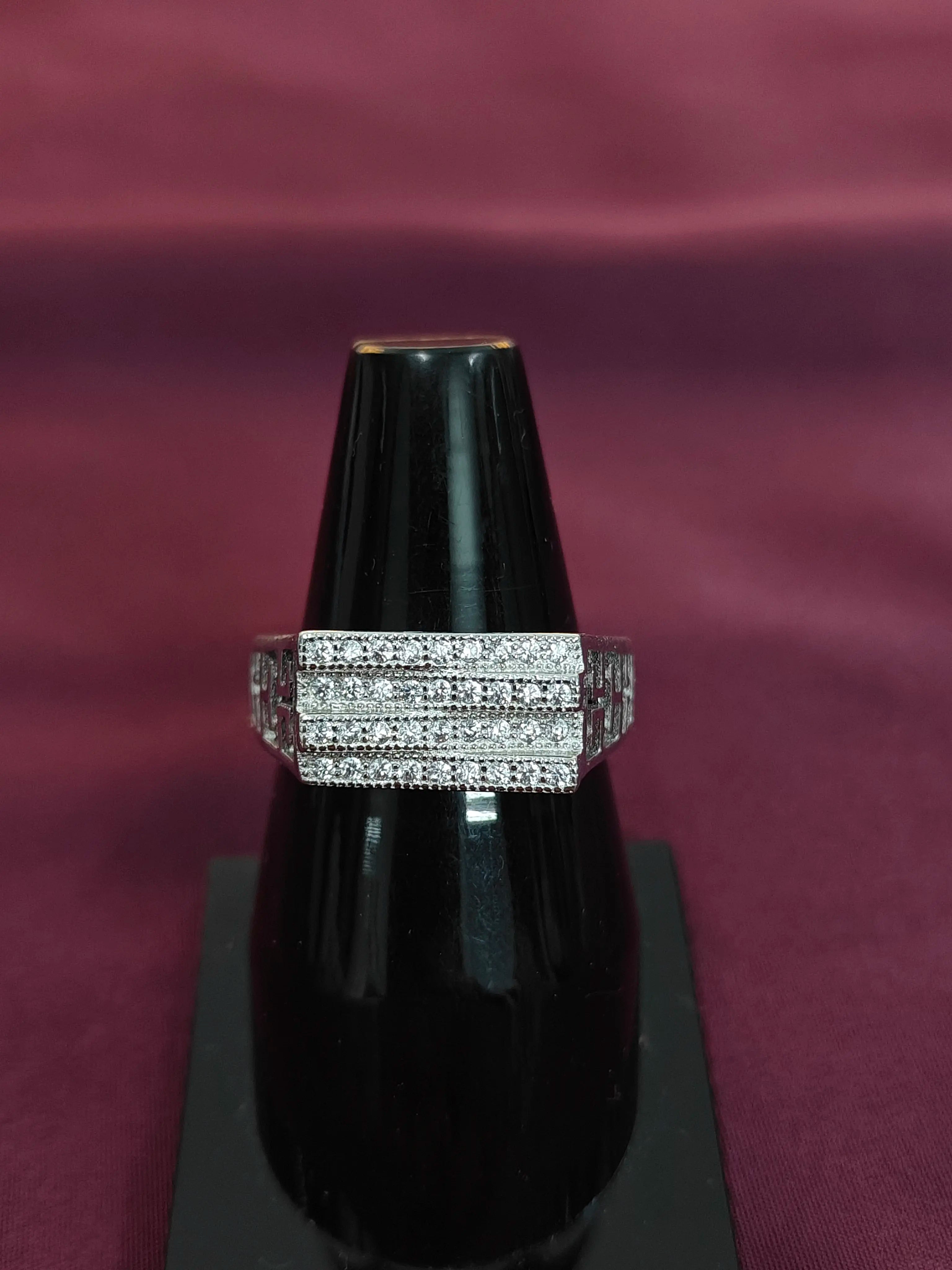 Silver ring with multiple bands on a black stand against a maroon background