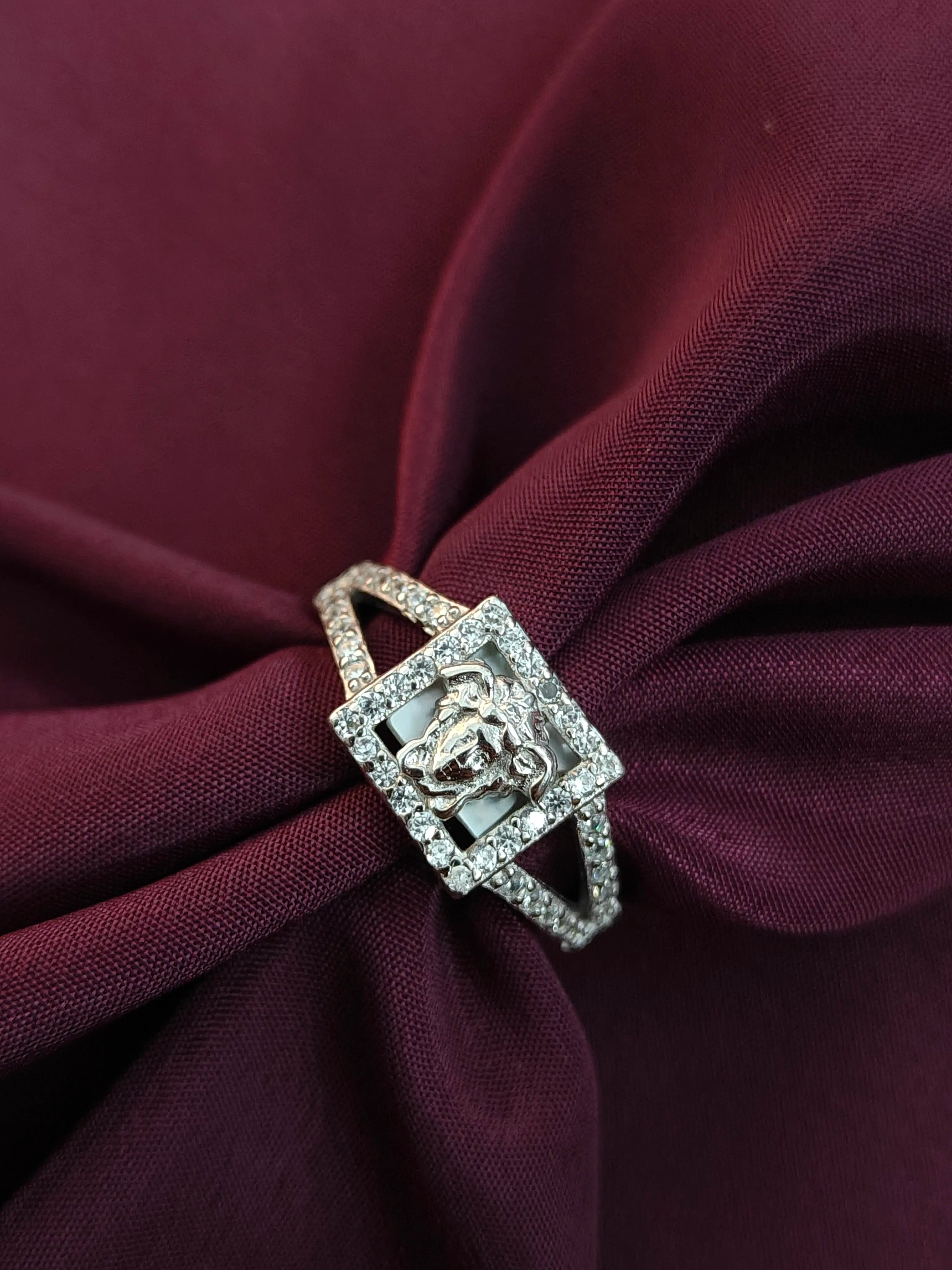 Silver ring with a decorative design on a burgundy fabric background