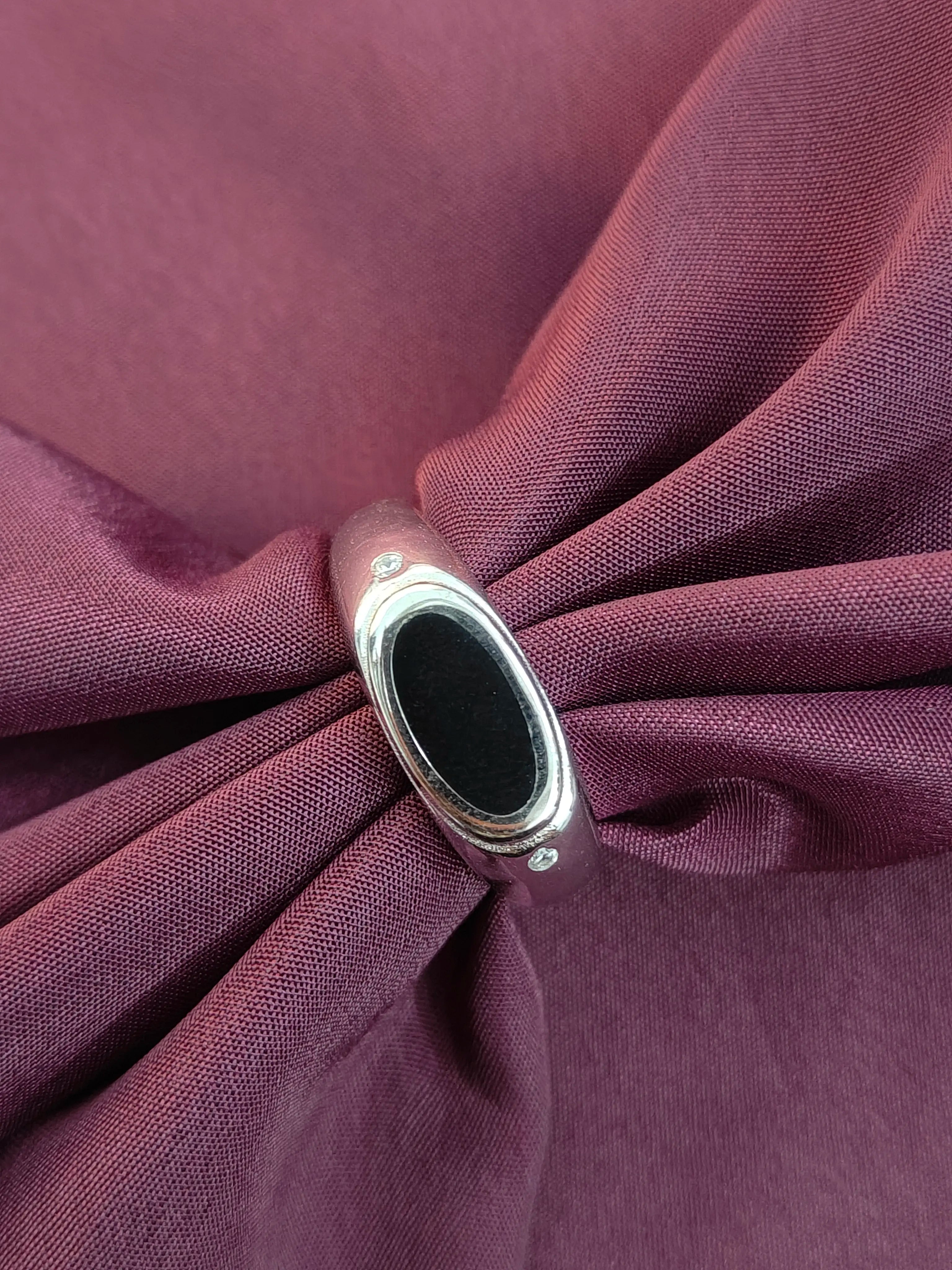 Close-up of a silver ring with a black stone on a purple fabric background