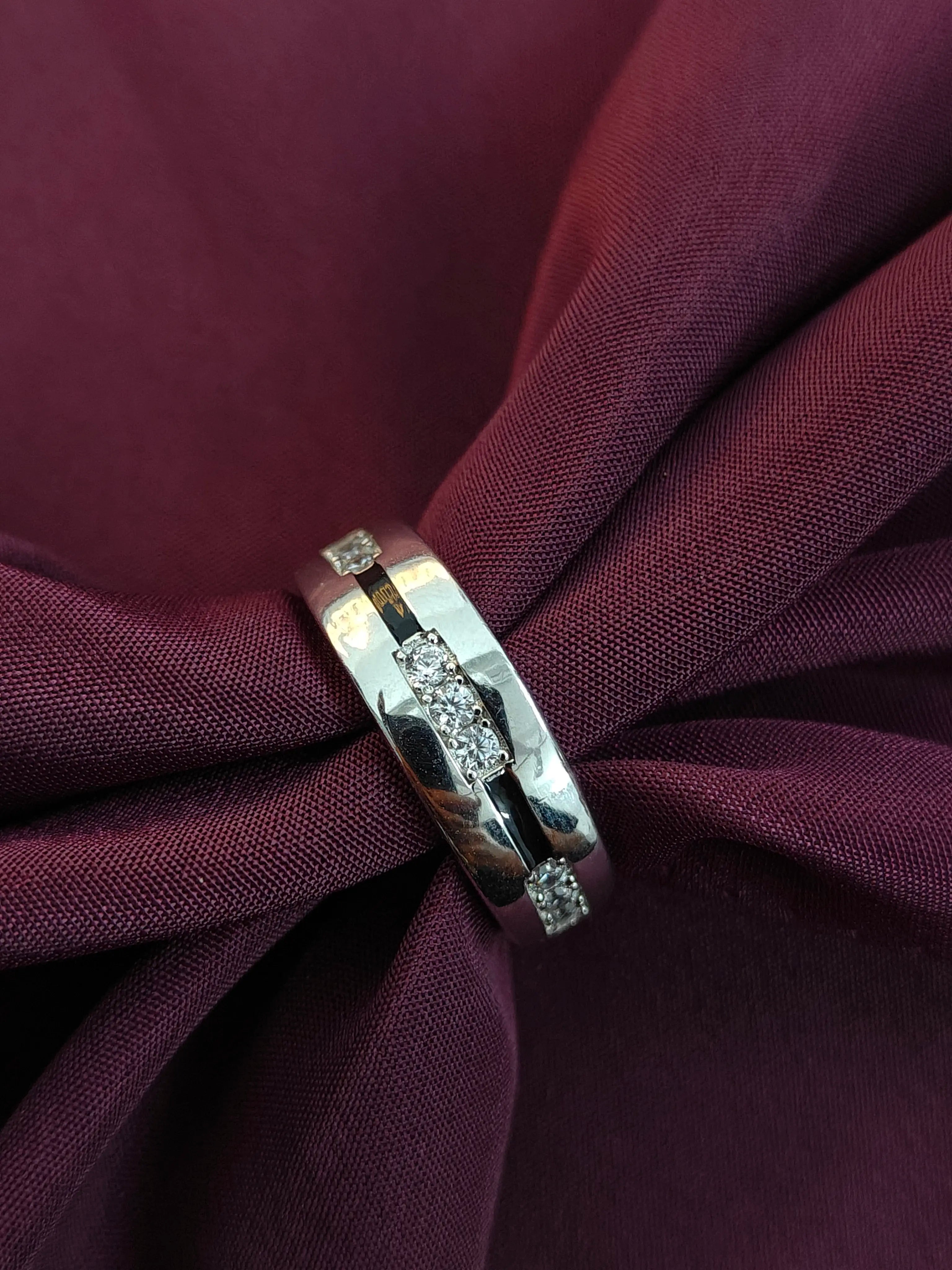 Silver ring with a diamond on a burgundy fabric background