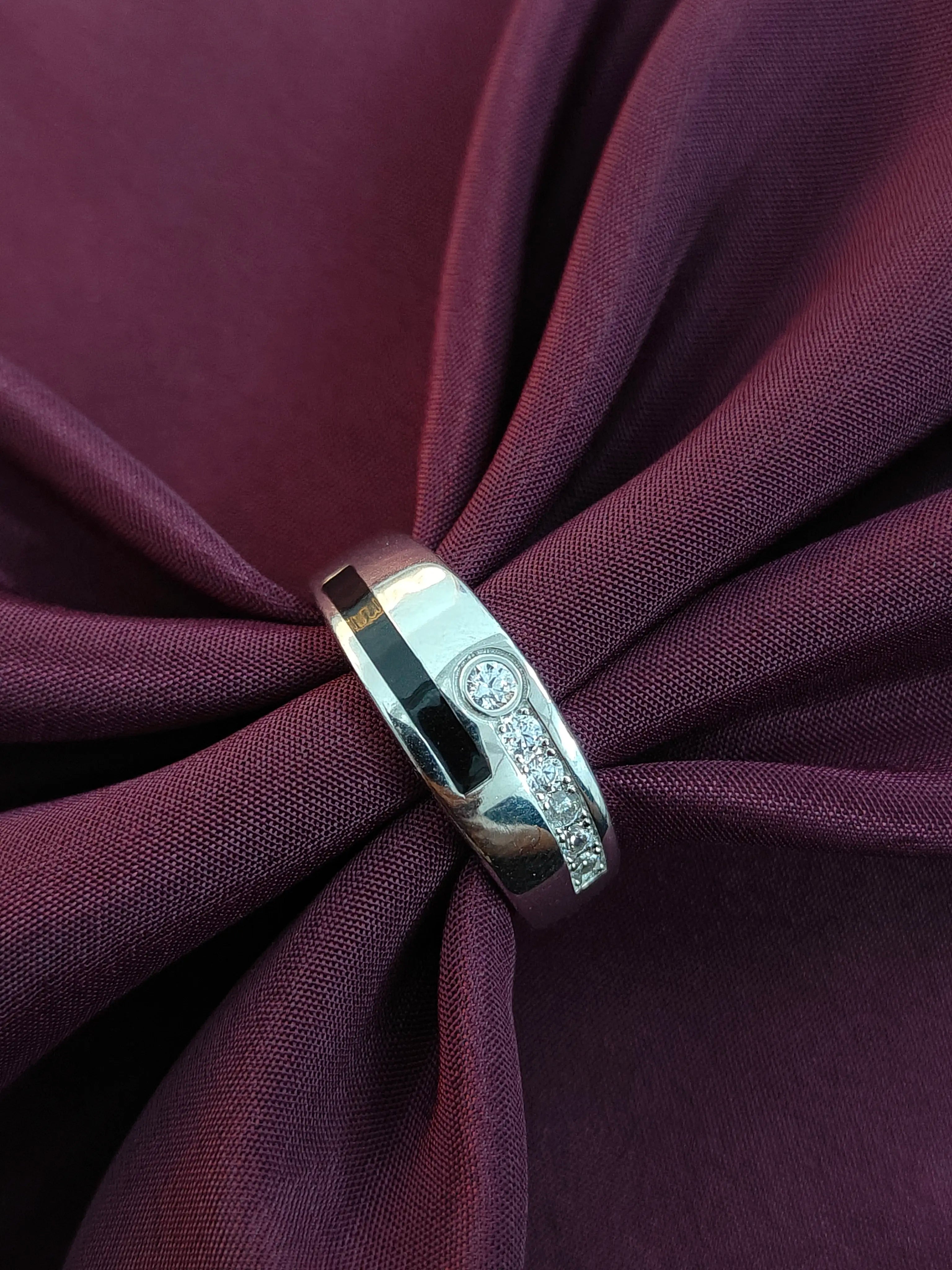 Silver ring with diamonds on a purple fabric background