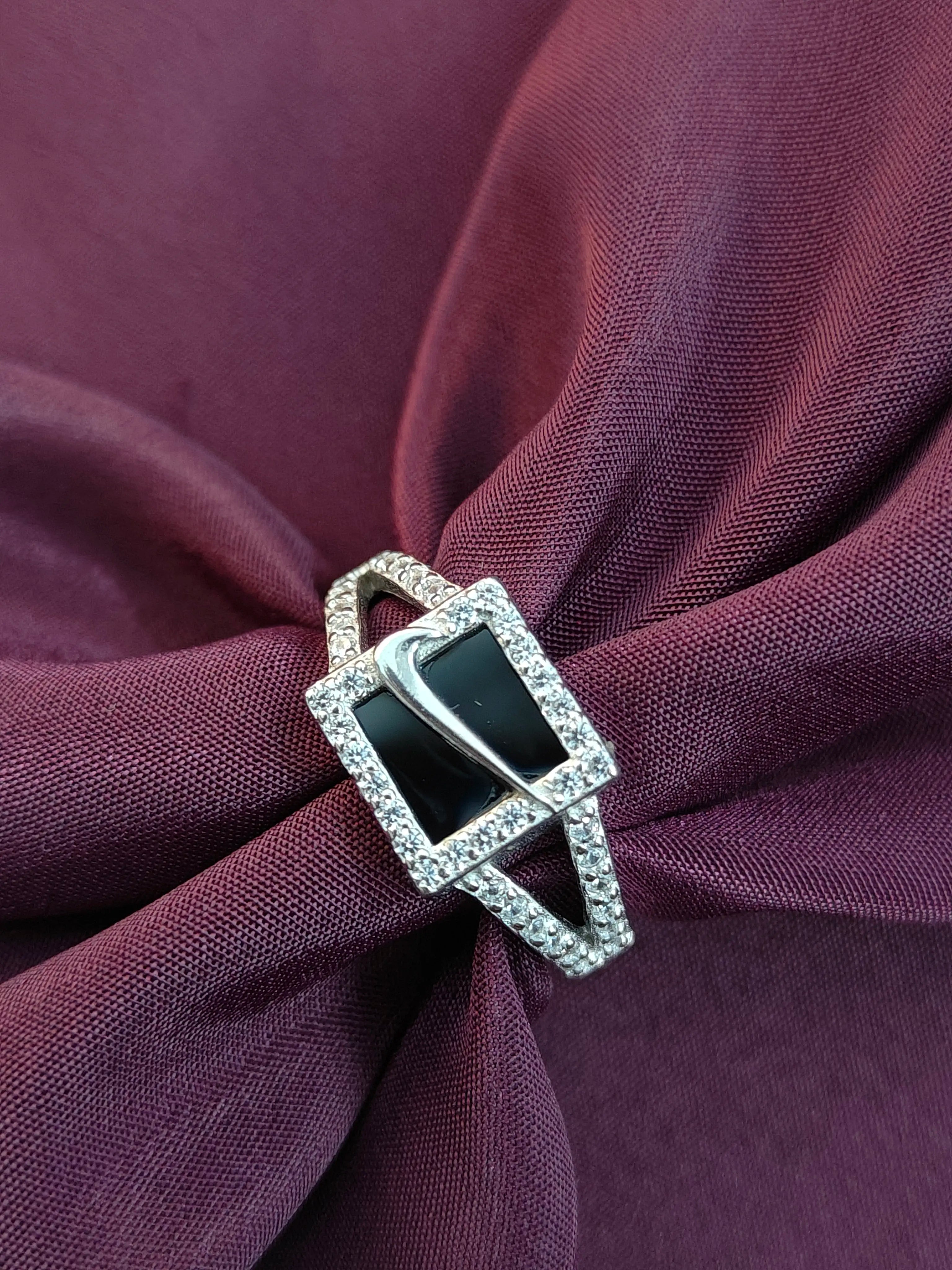 Silver ring with black gemstone on a purple fabric background