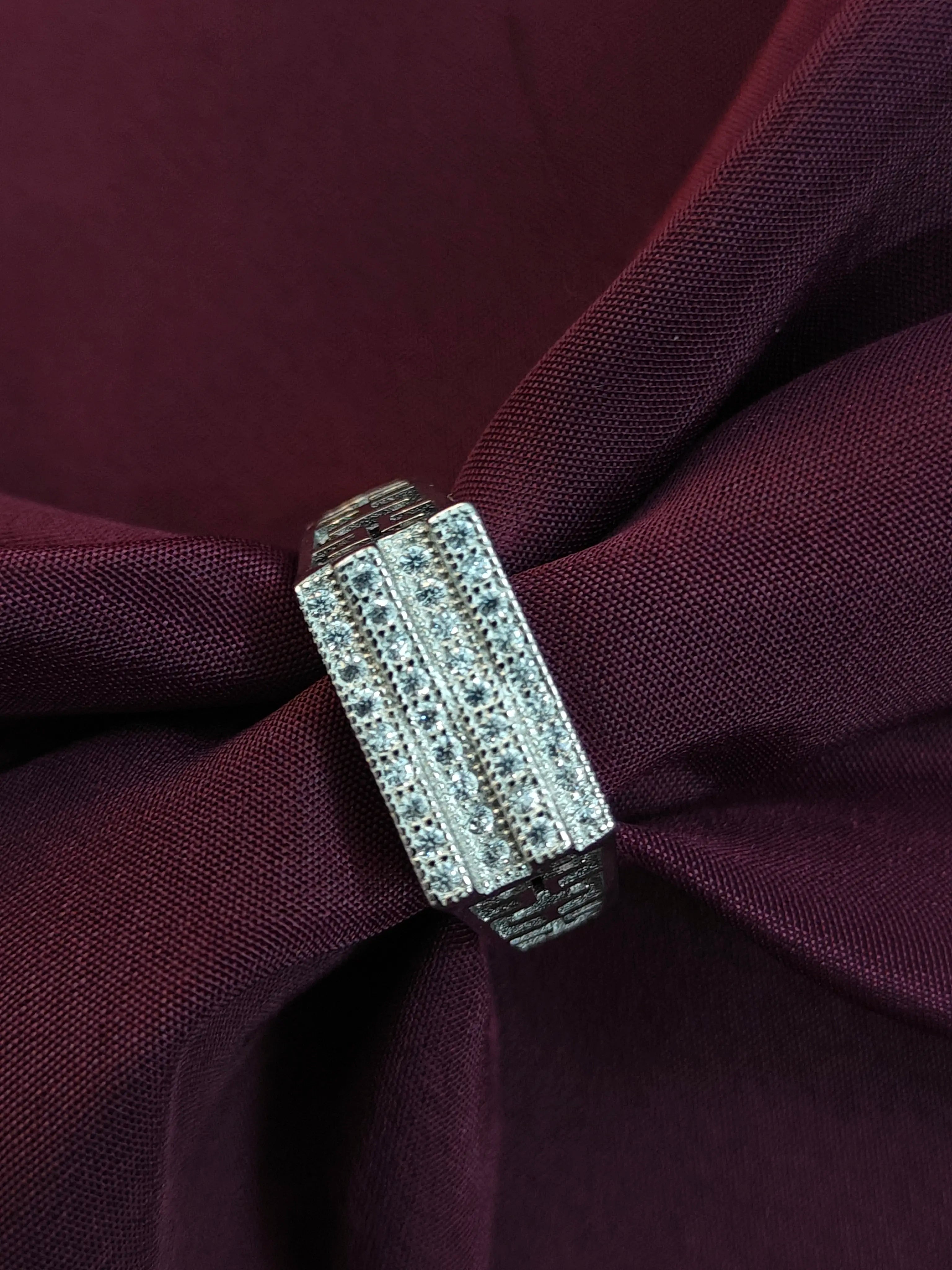 Close-up of a decorative brooch on a burgundy fabric background