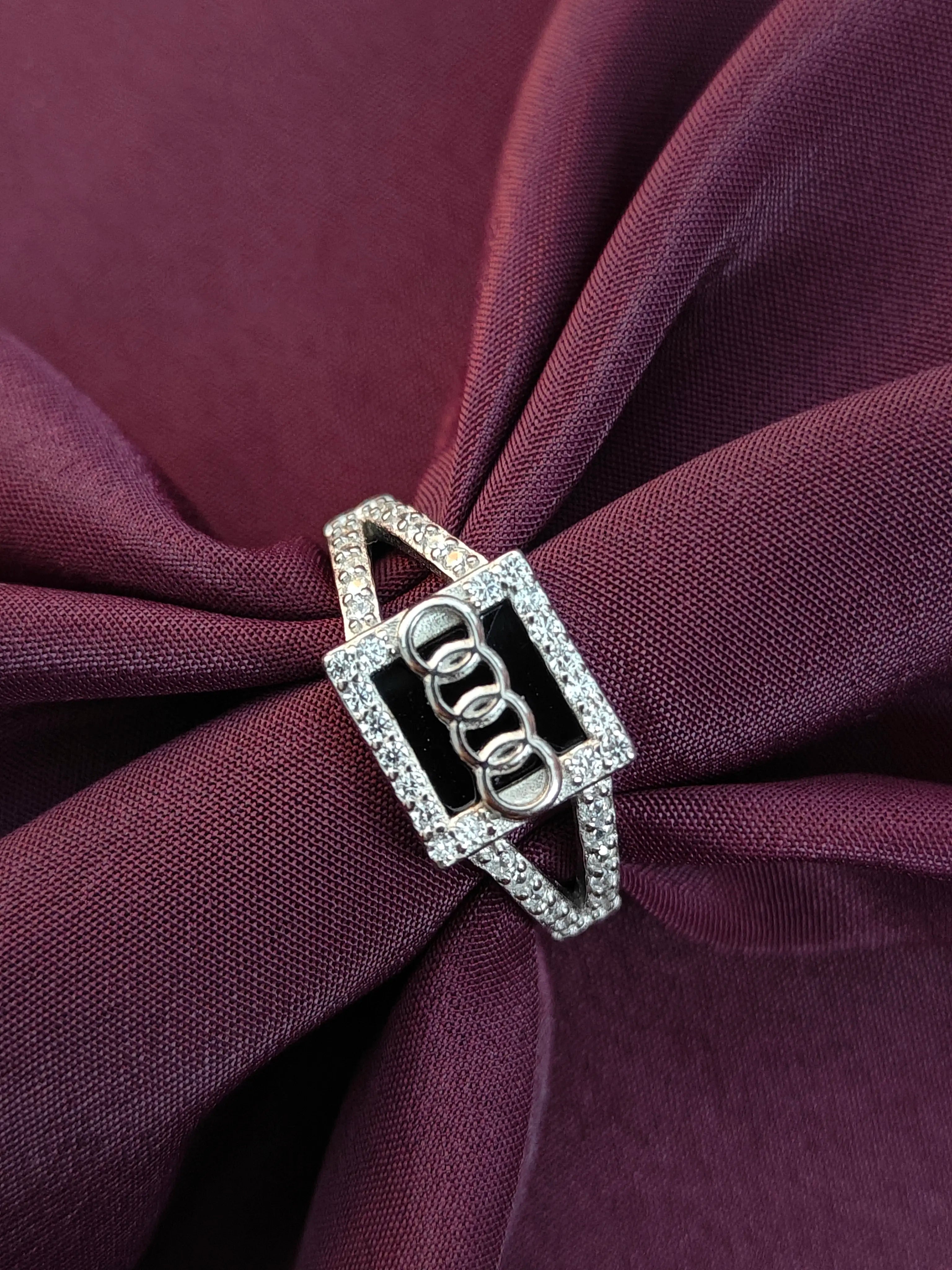 Silver brooch with gemstones on a purple fabric background