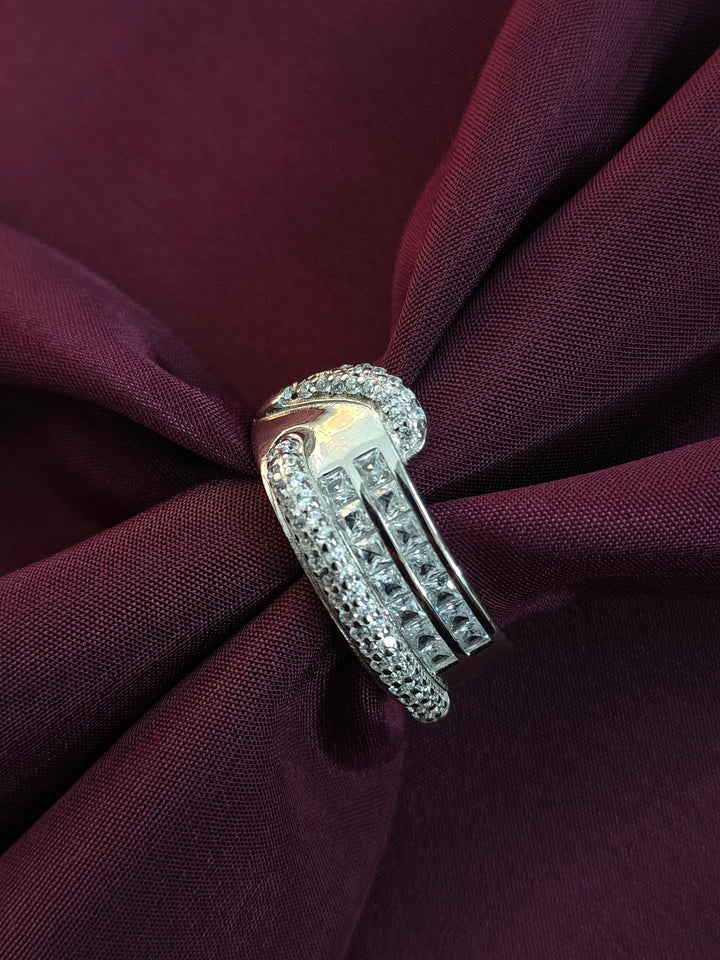 Silver ring with gemstones on a burgundy fabric background