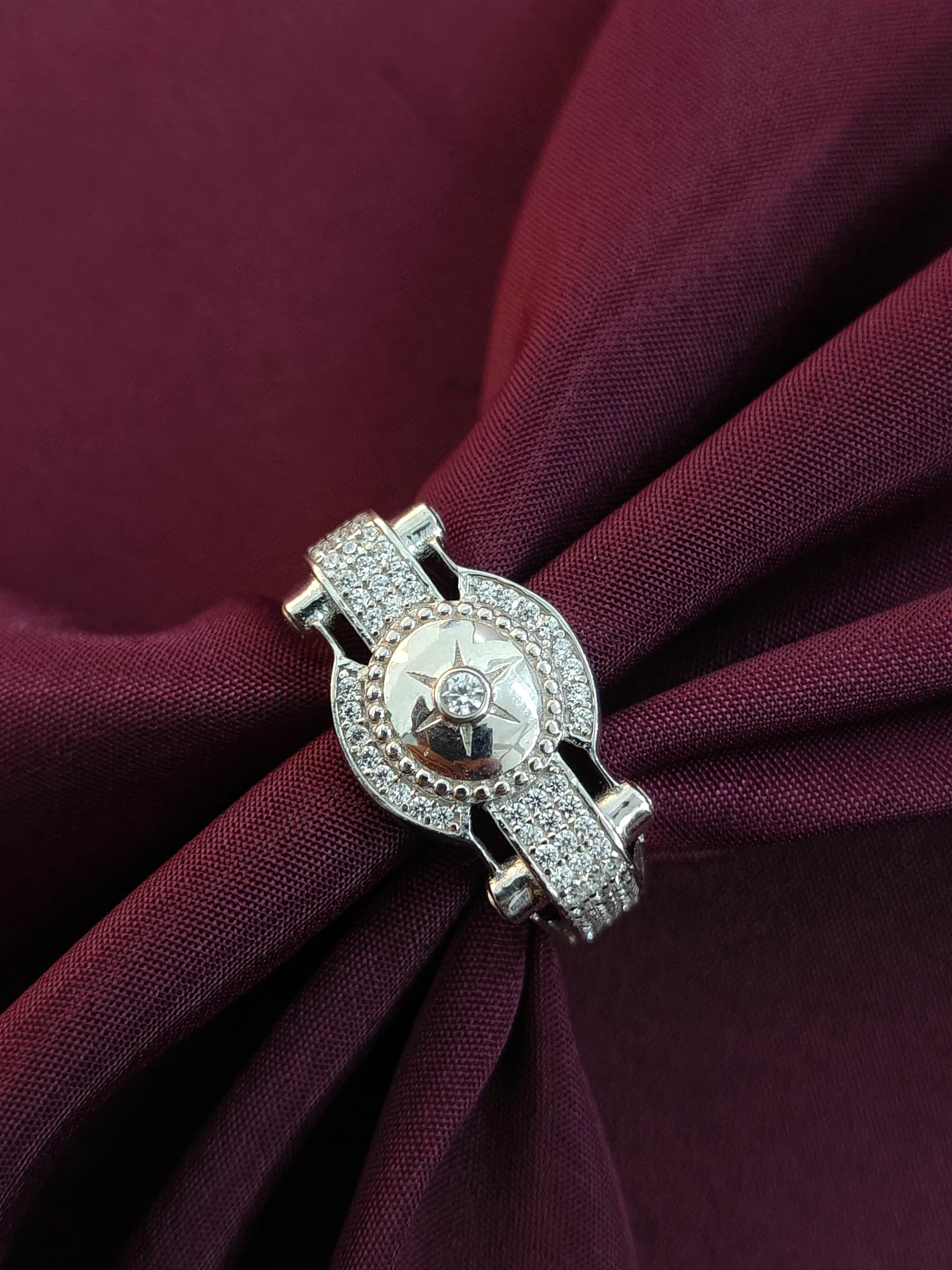 Silver brooch with star design on a burgundy fabric background