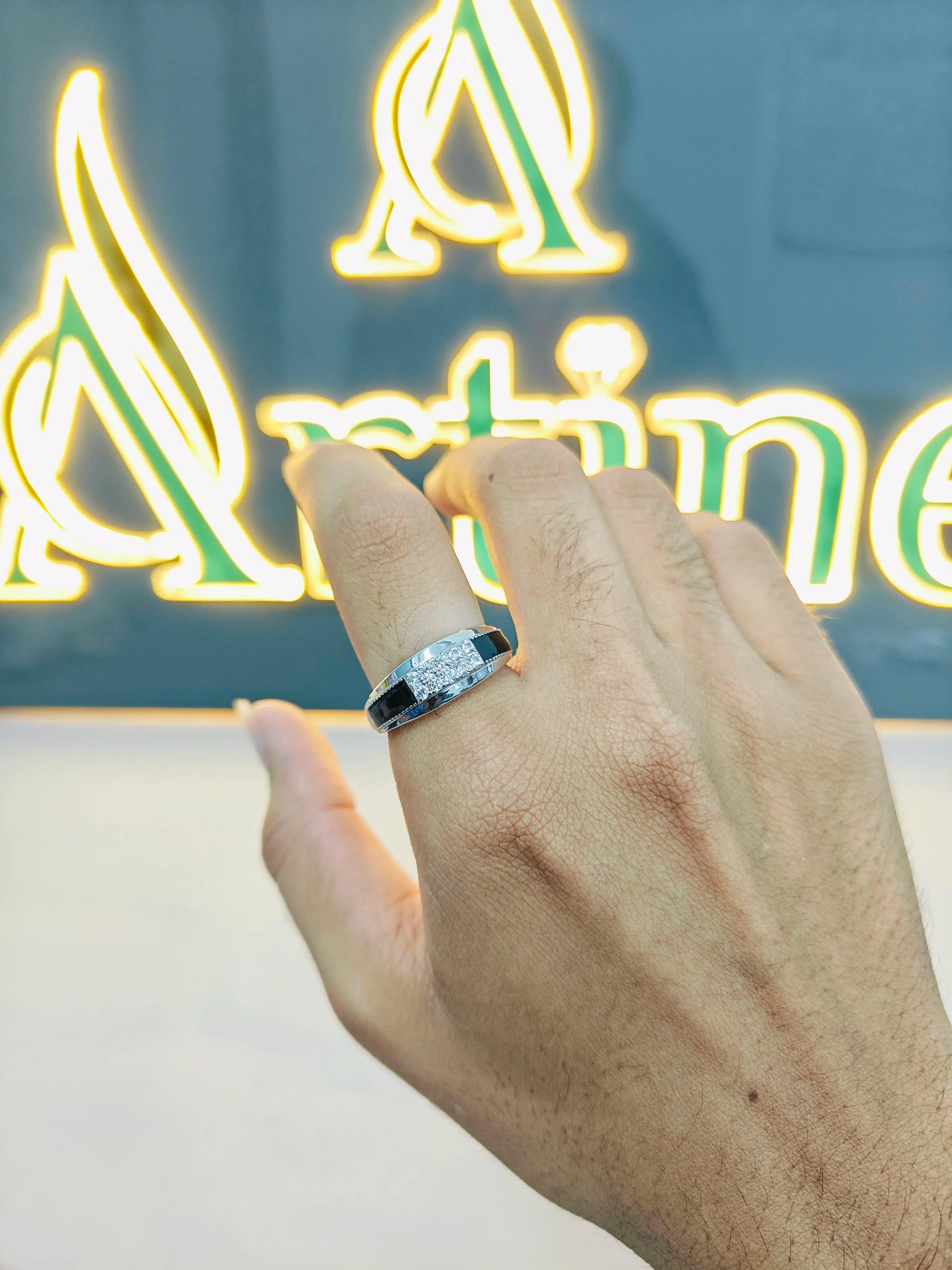 Hand wearing a ring with a neon sign in the background