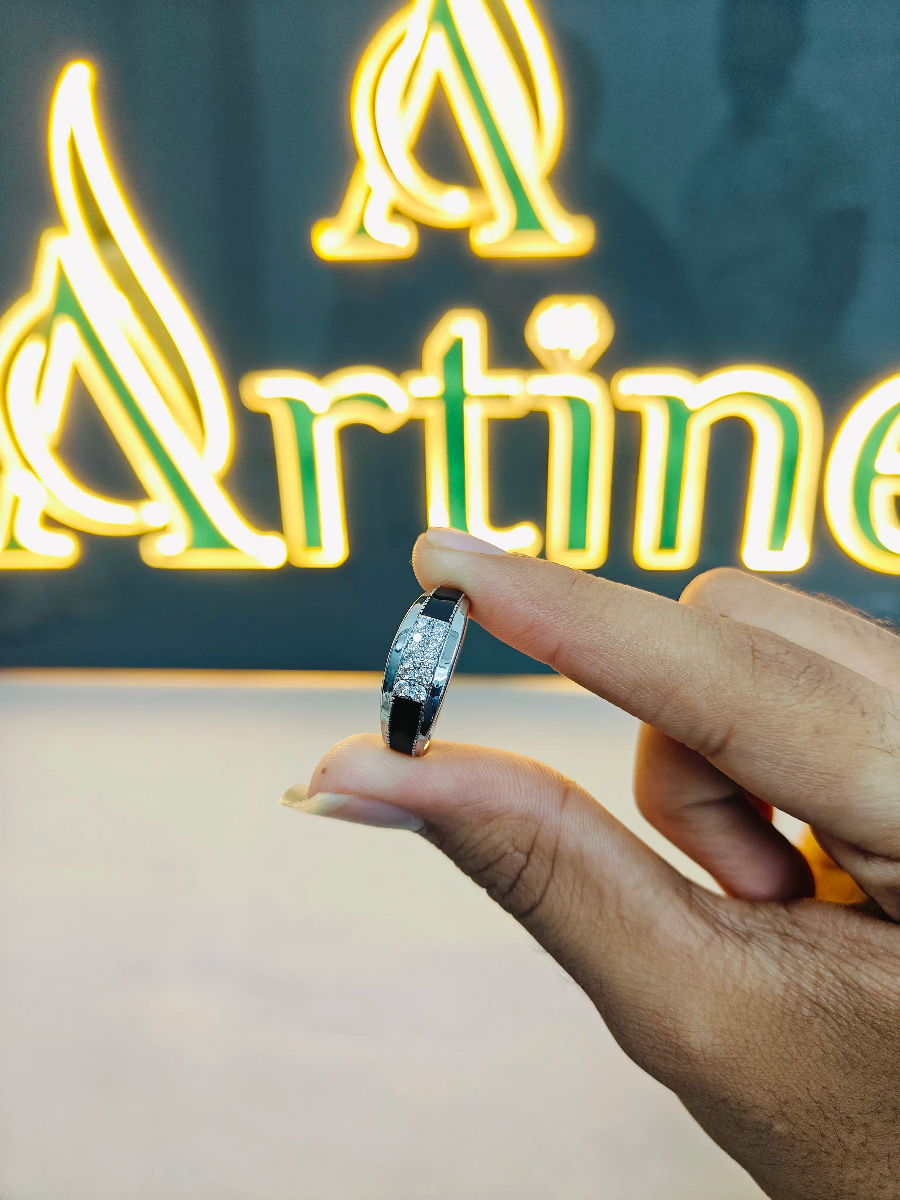 Hand holding a ring with a neon sign in the background