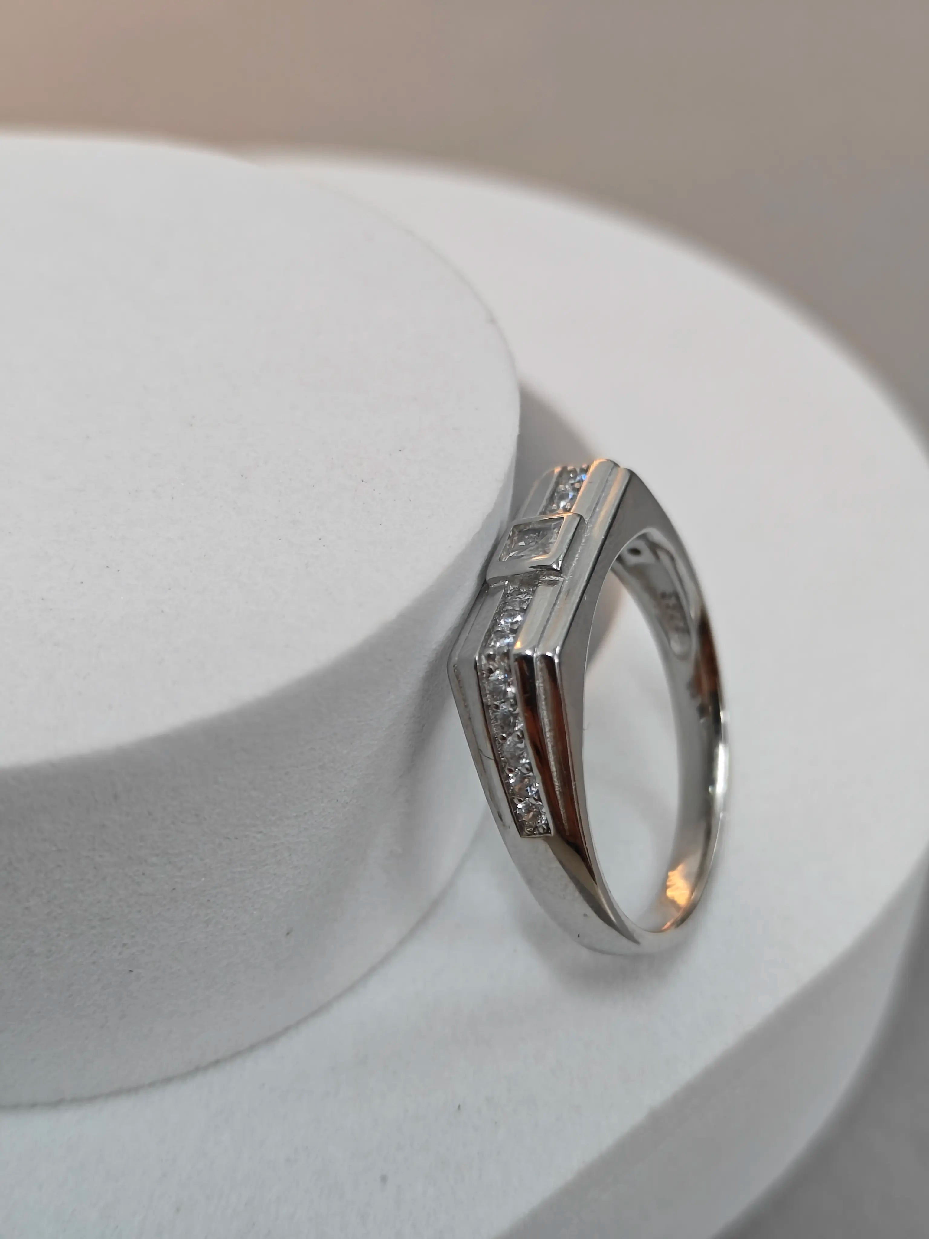 Silver ring with small diamonds on a white stand