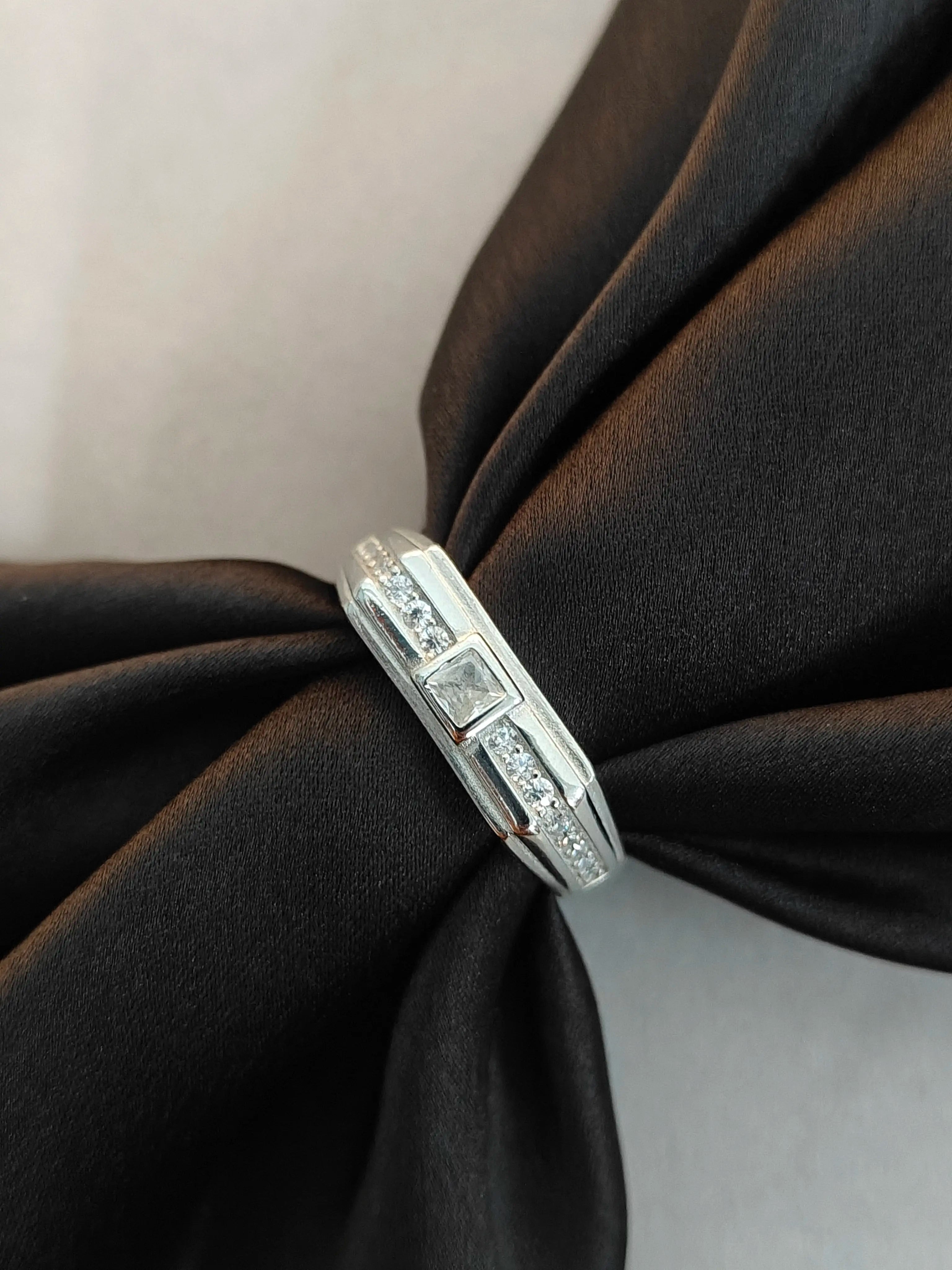 Silver ring with diamonds on a black fabric background