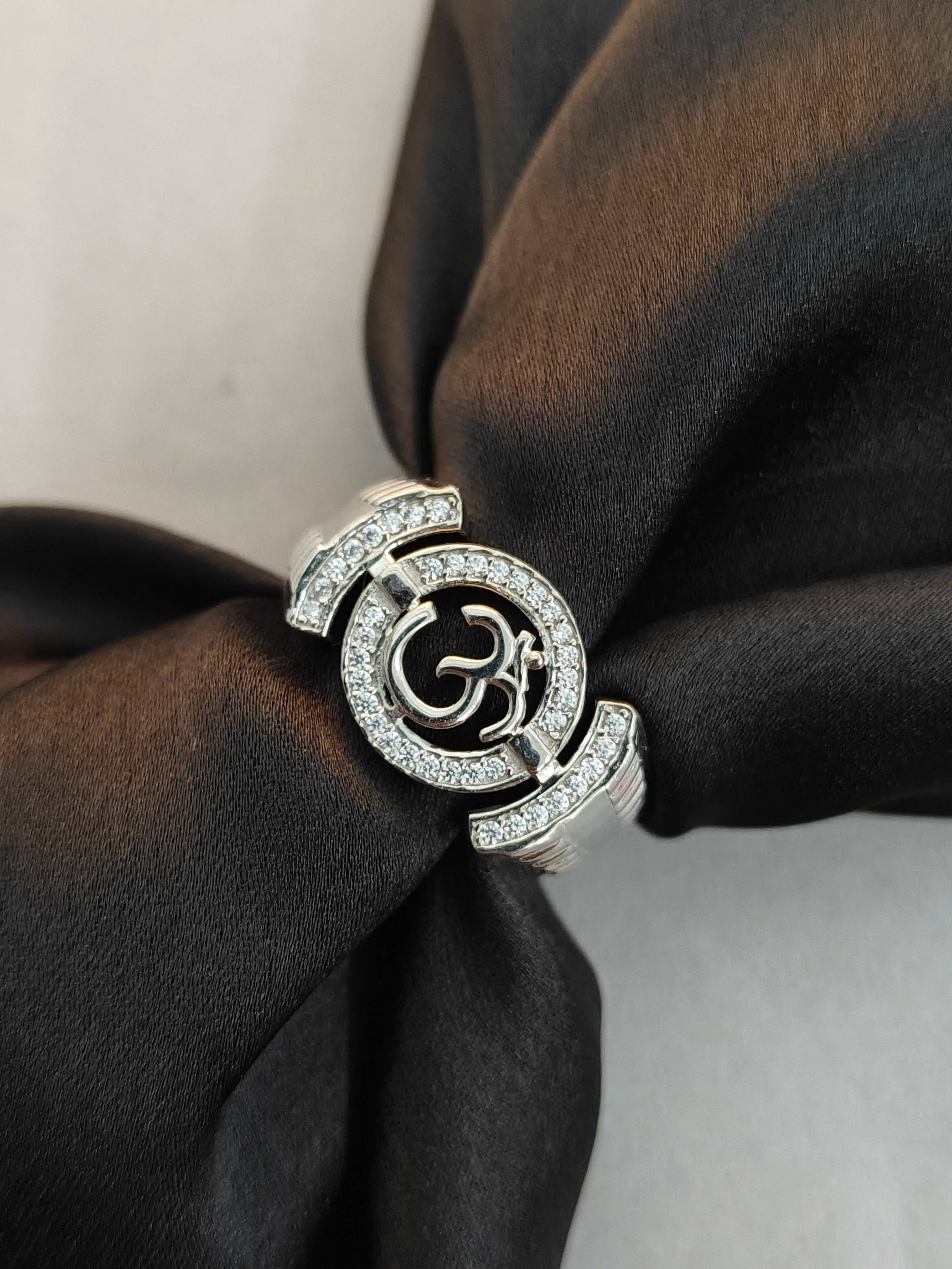 Silver ring with a logo on a black fabric background