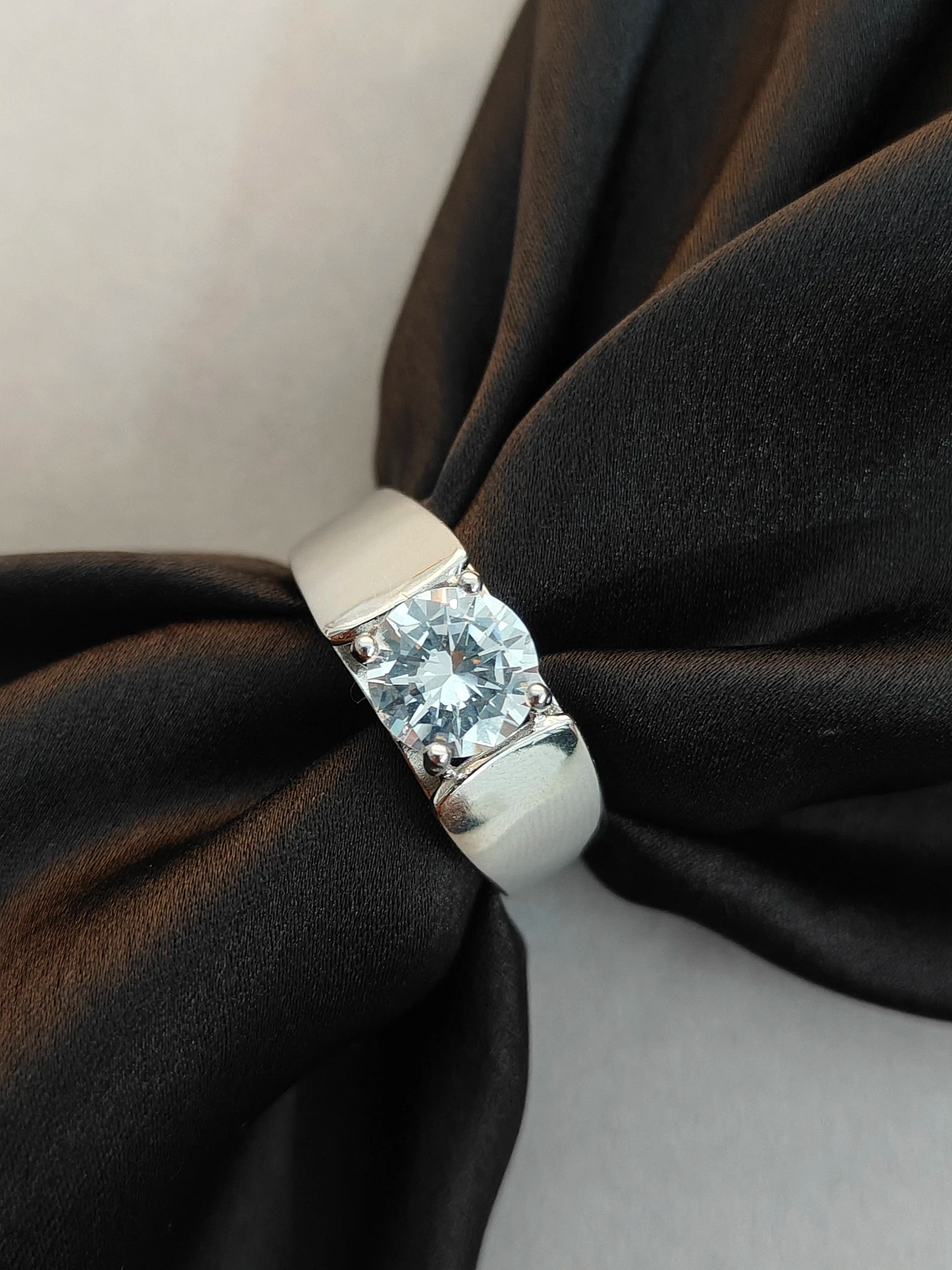 Silver ring with a large diamond on a black fabric background