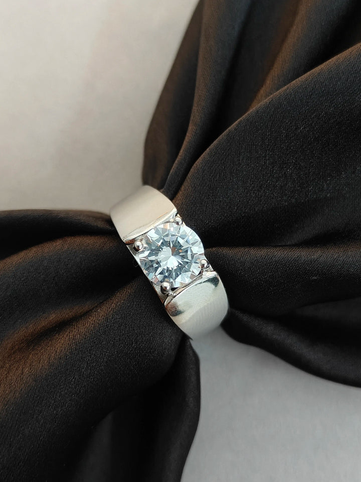Silver ring with a large diamond on a black fabric background