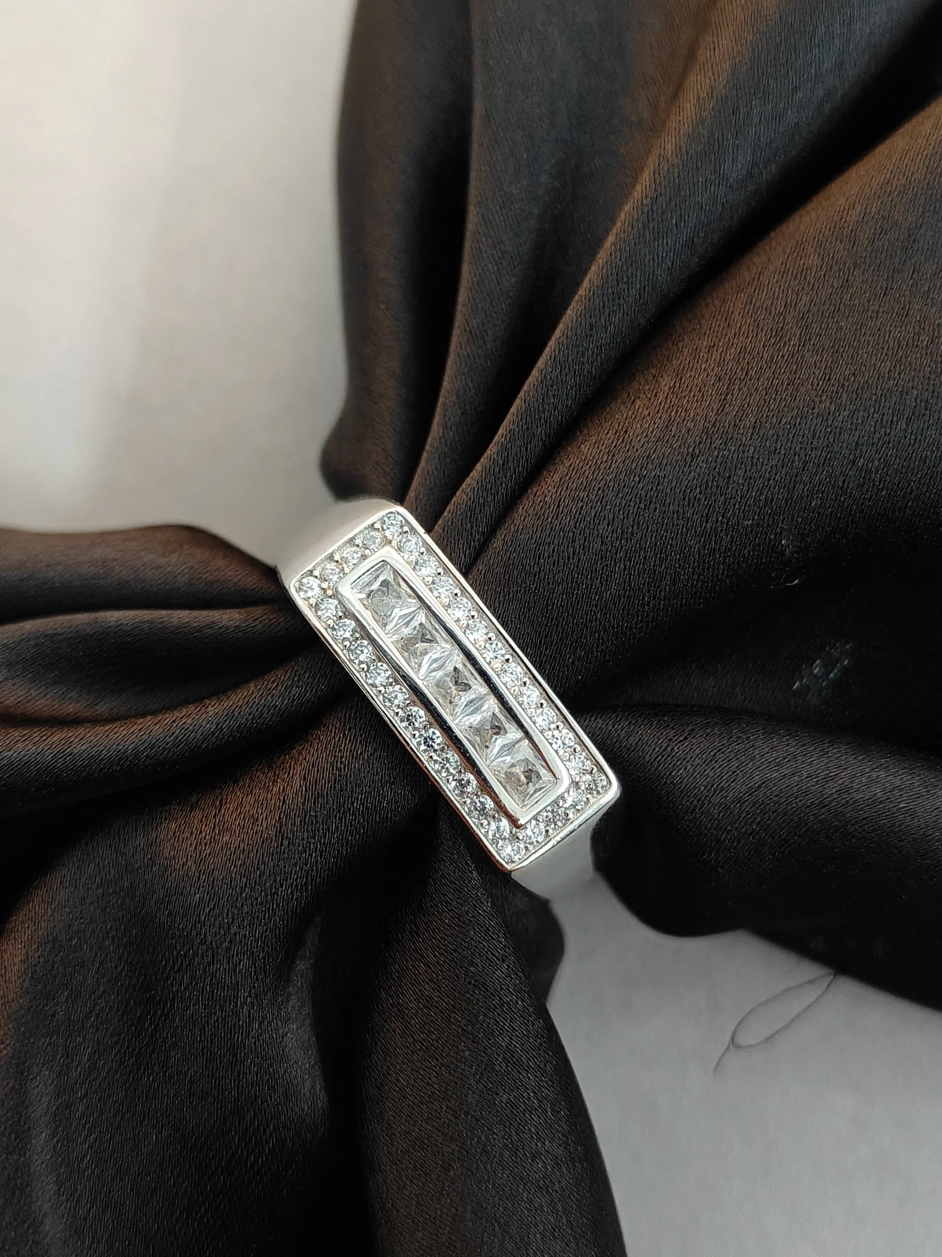 Silver ring with diamonds on a black fabric background