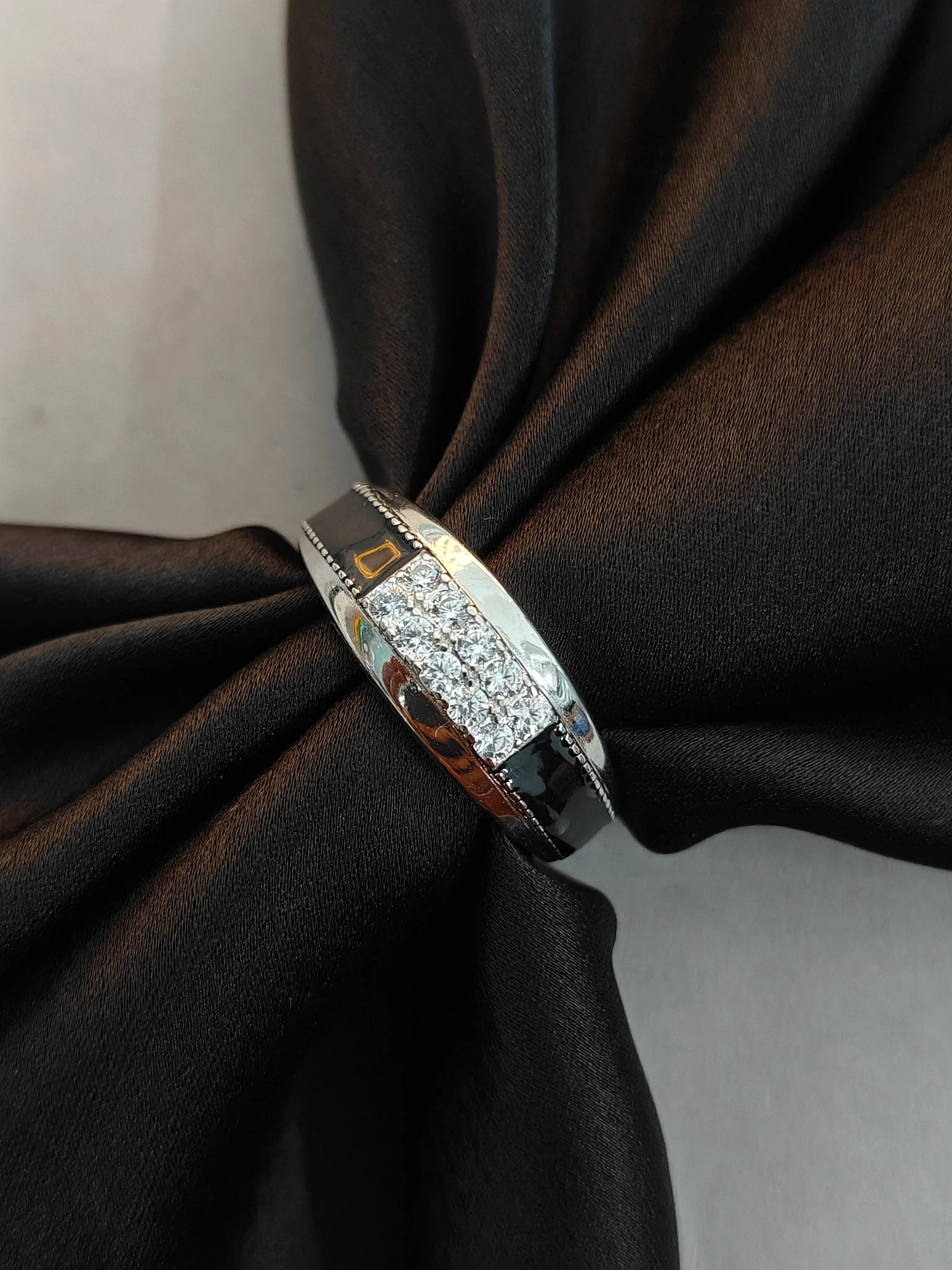 Silver ring with embedded stones on a black fabric background