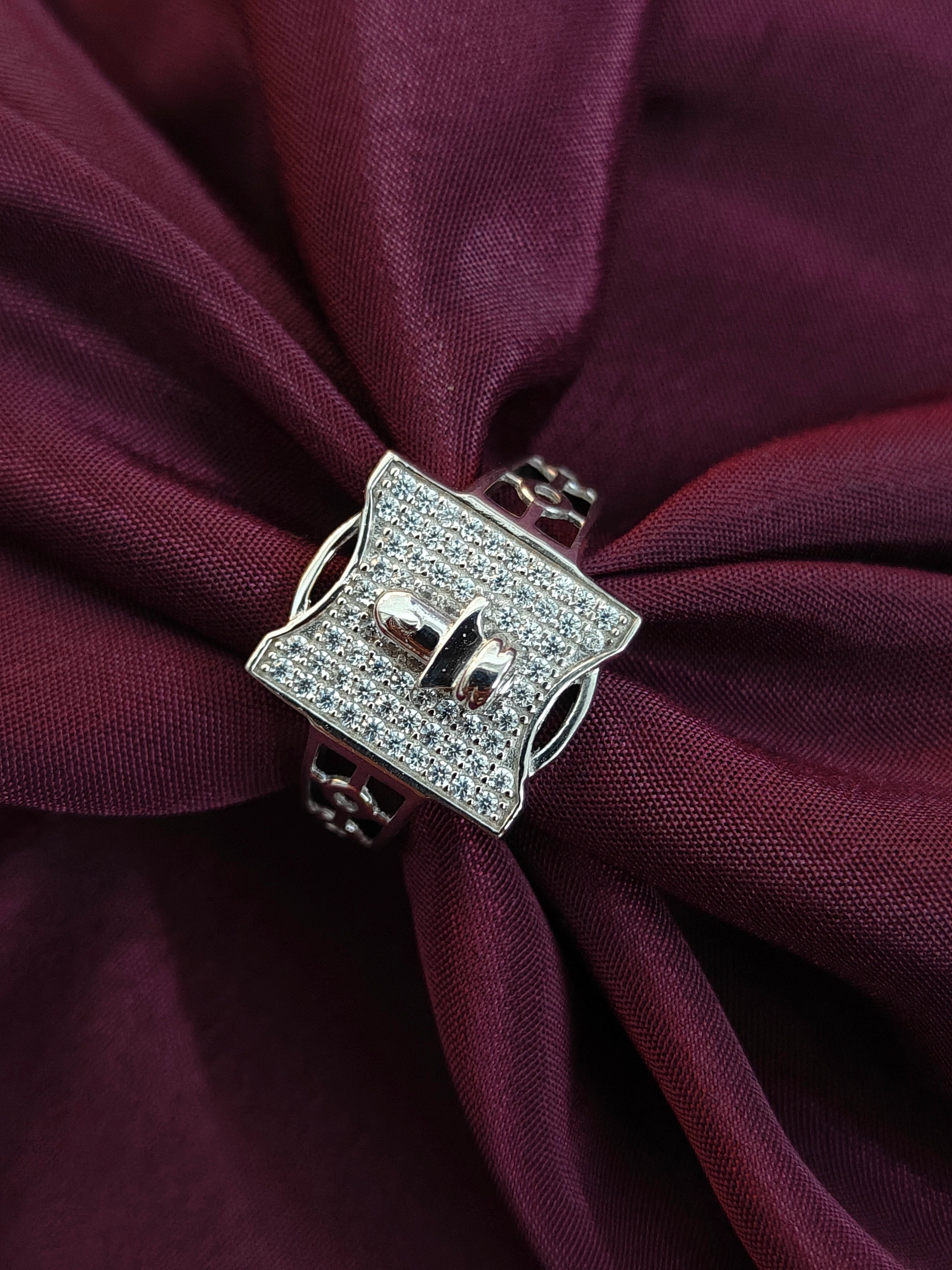 Silver belt buckle with clear stones on a purple fabric background