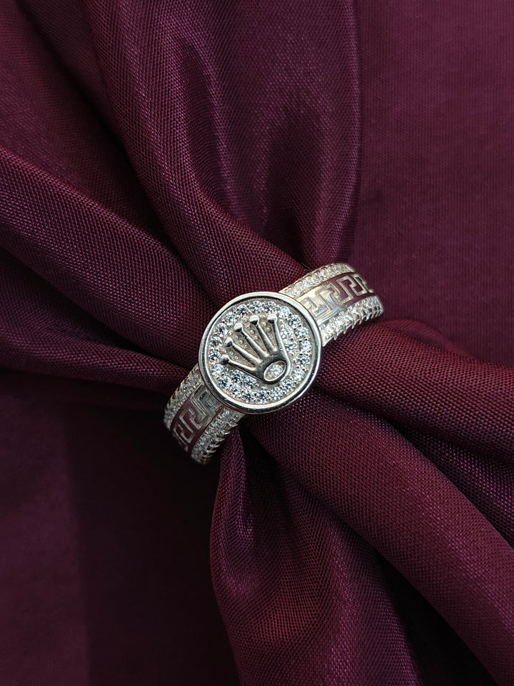 Silver ring with a logo on a maroon fabric background