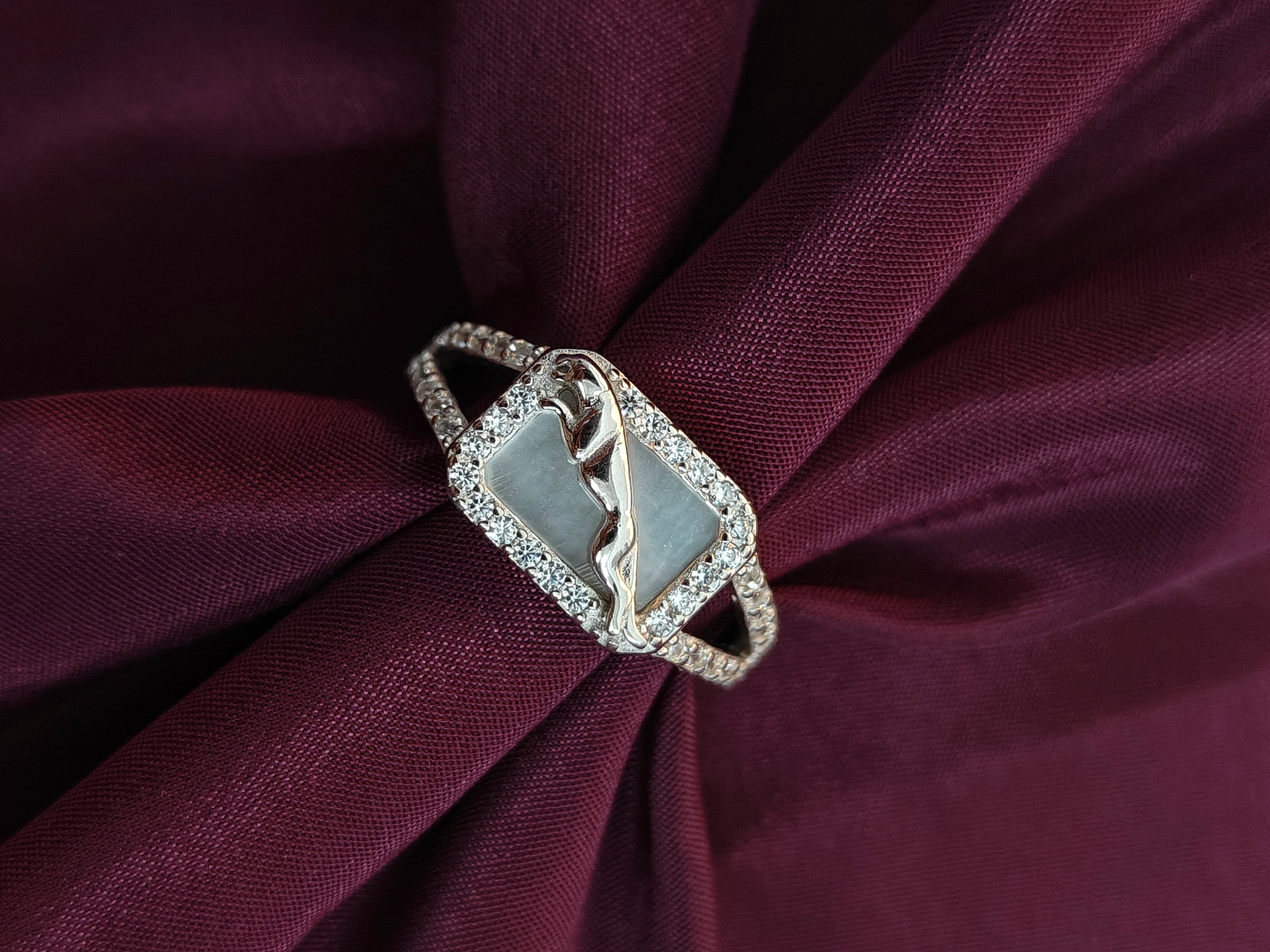 Silver ring with a diamond on a burgundy fabric background