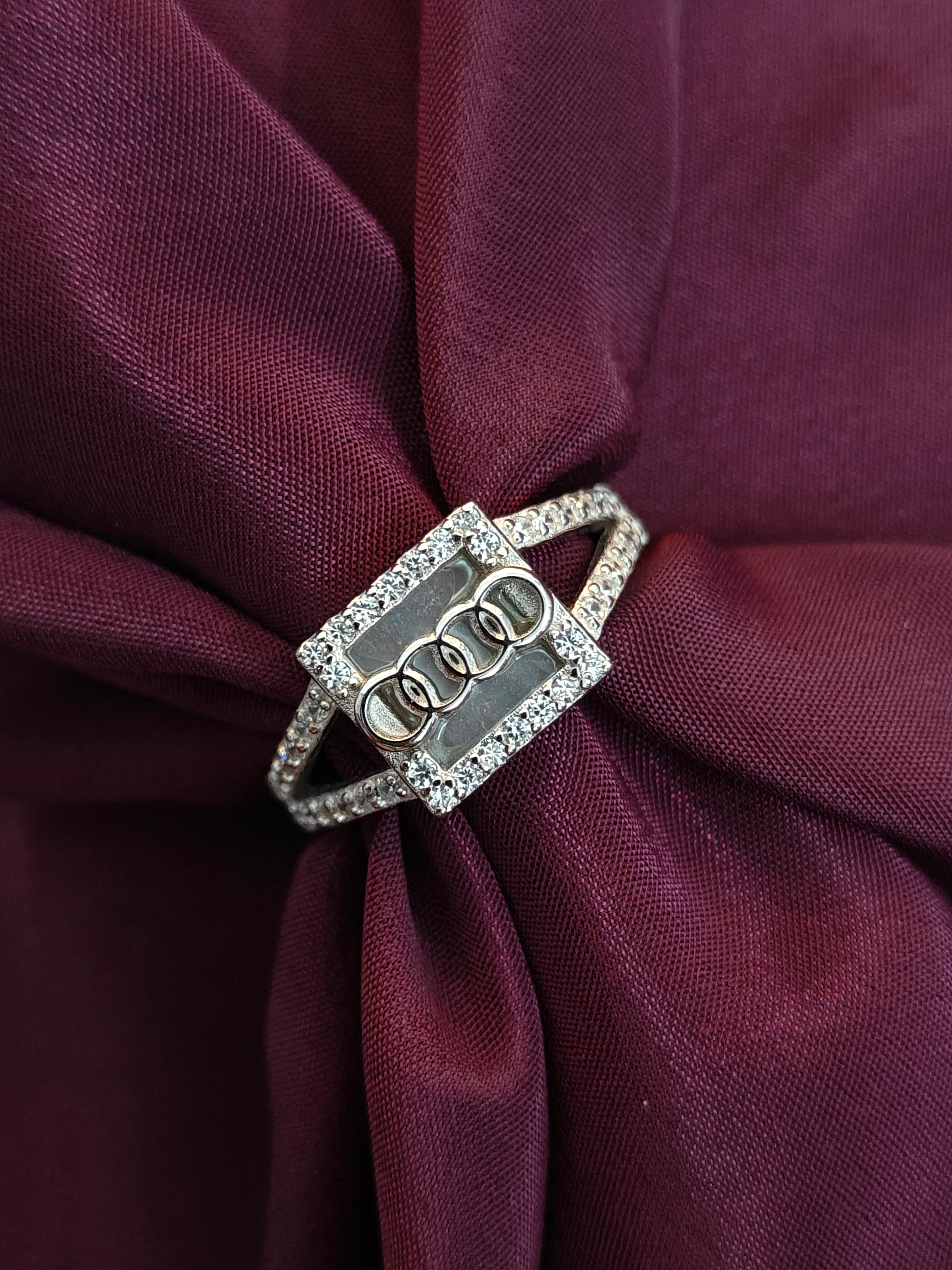 Silver ring with three interlocking circles on a burgundy fabric background