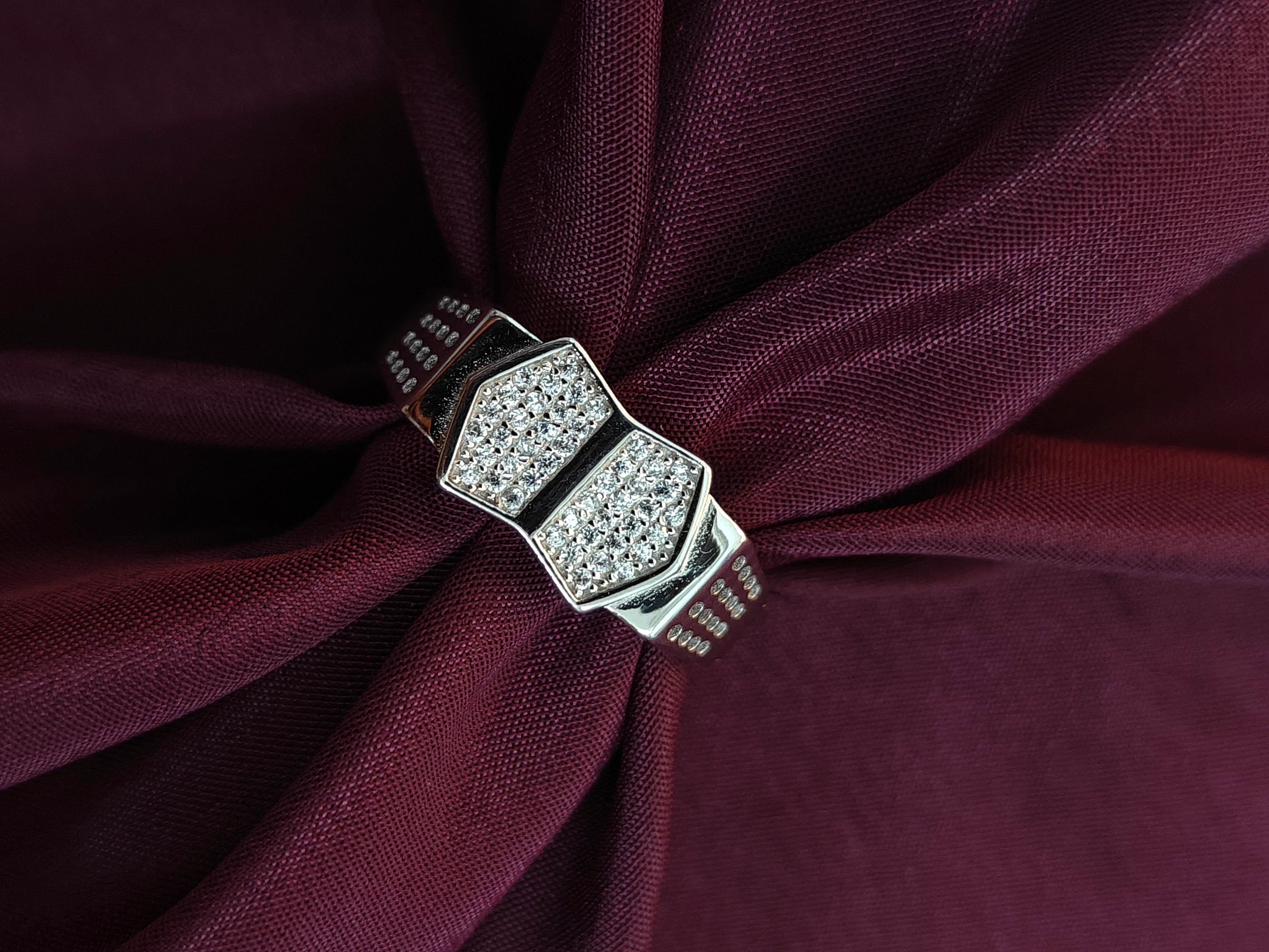 Silver ring with gemstones on a burgundy fabric background