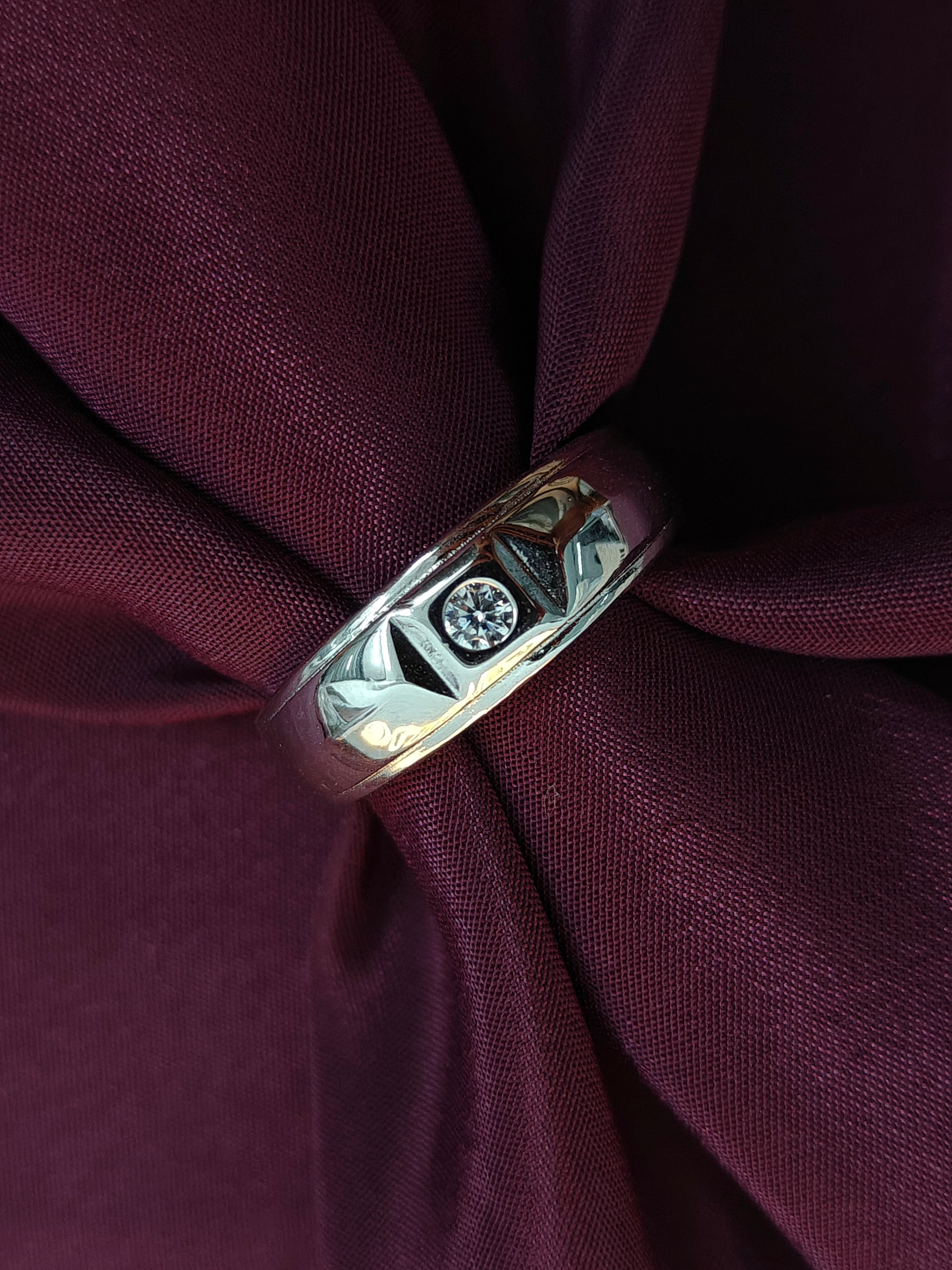 Silver ring with a diamond on a maroon fabric background
