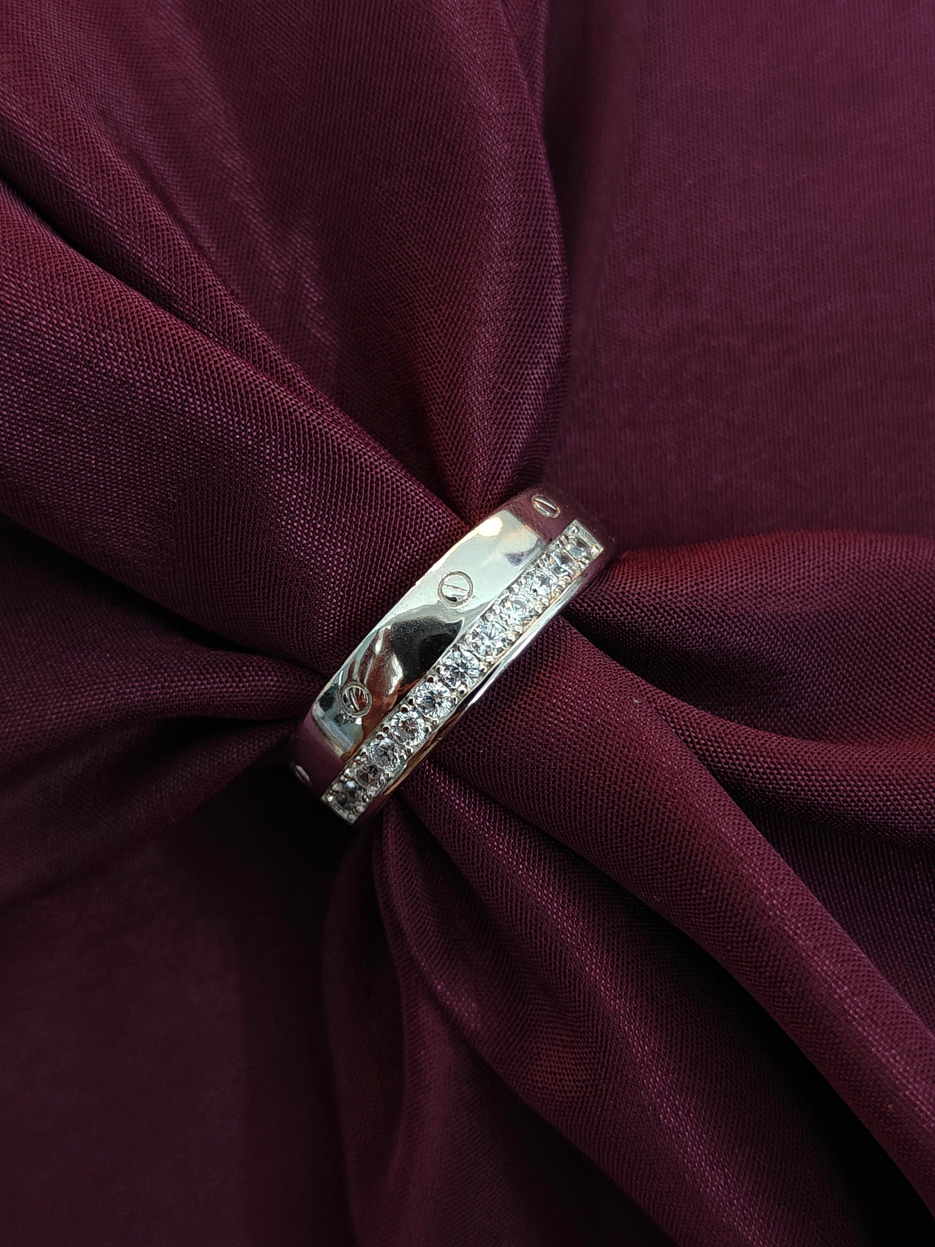 Silver ring with diamonds on a burgundy fabric background