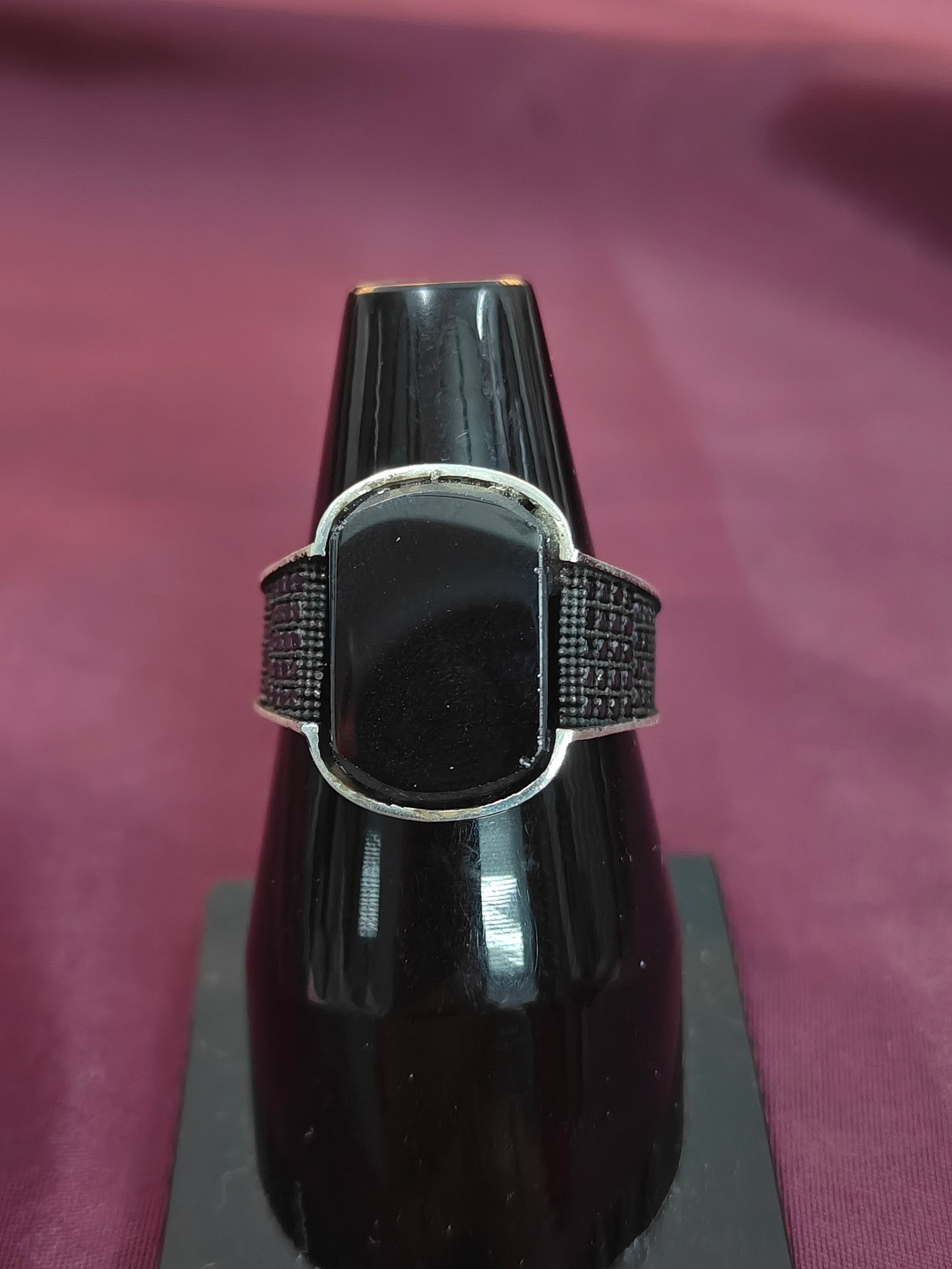 Black saxophone mouthpiece with silver band on a purple background