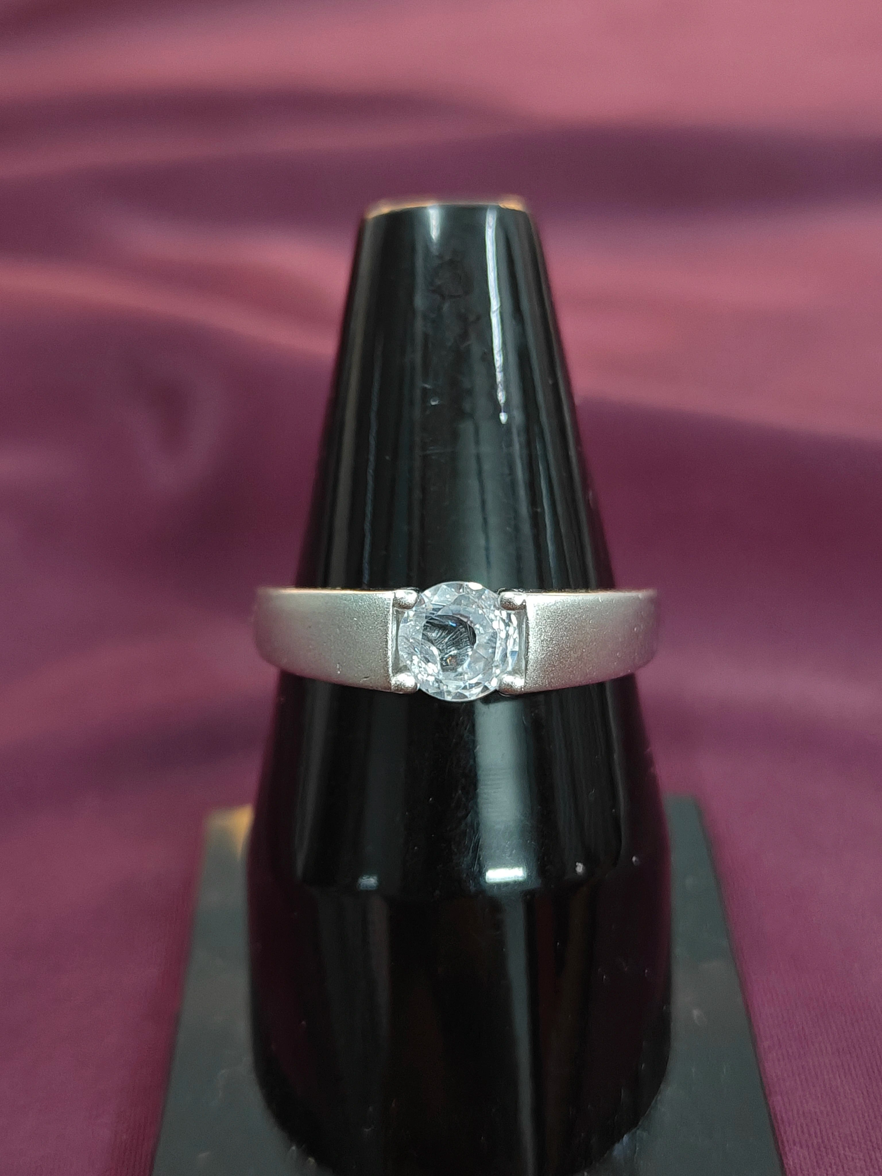 Diamond ring on a black stand against a purple background