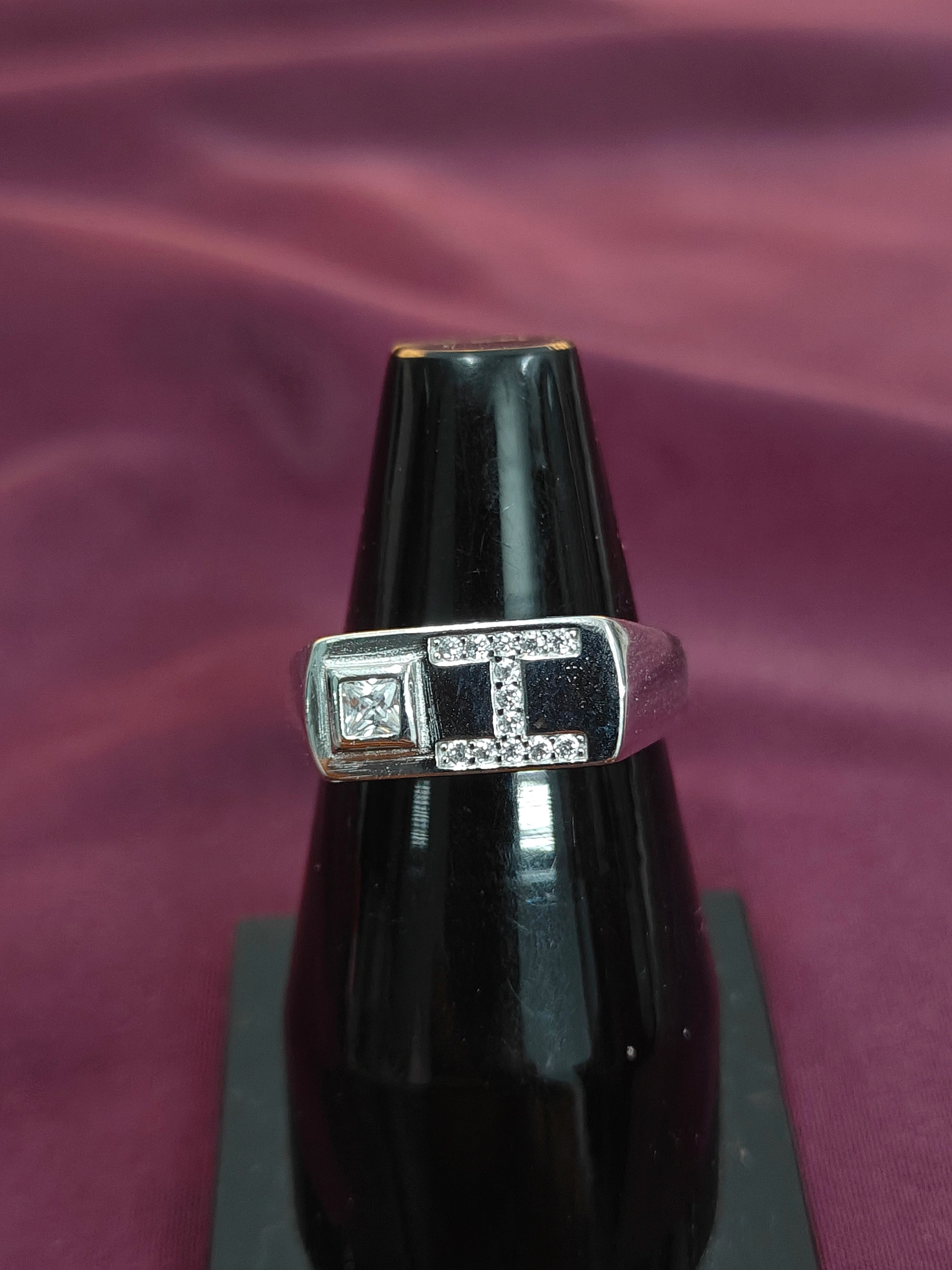 Silver ring with gemstones on a black stand against a purple fabric background