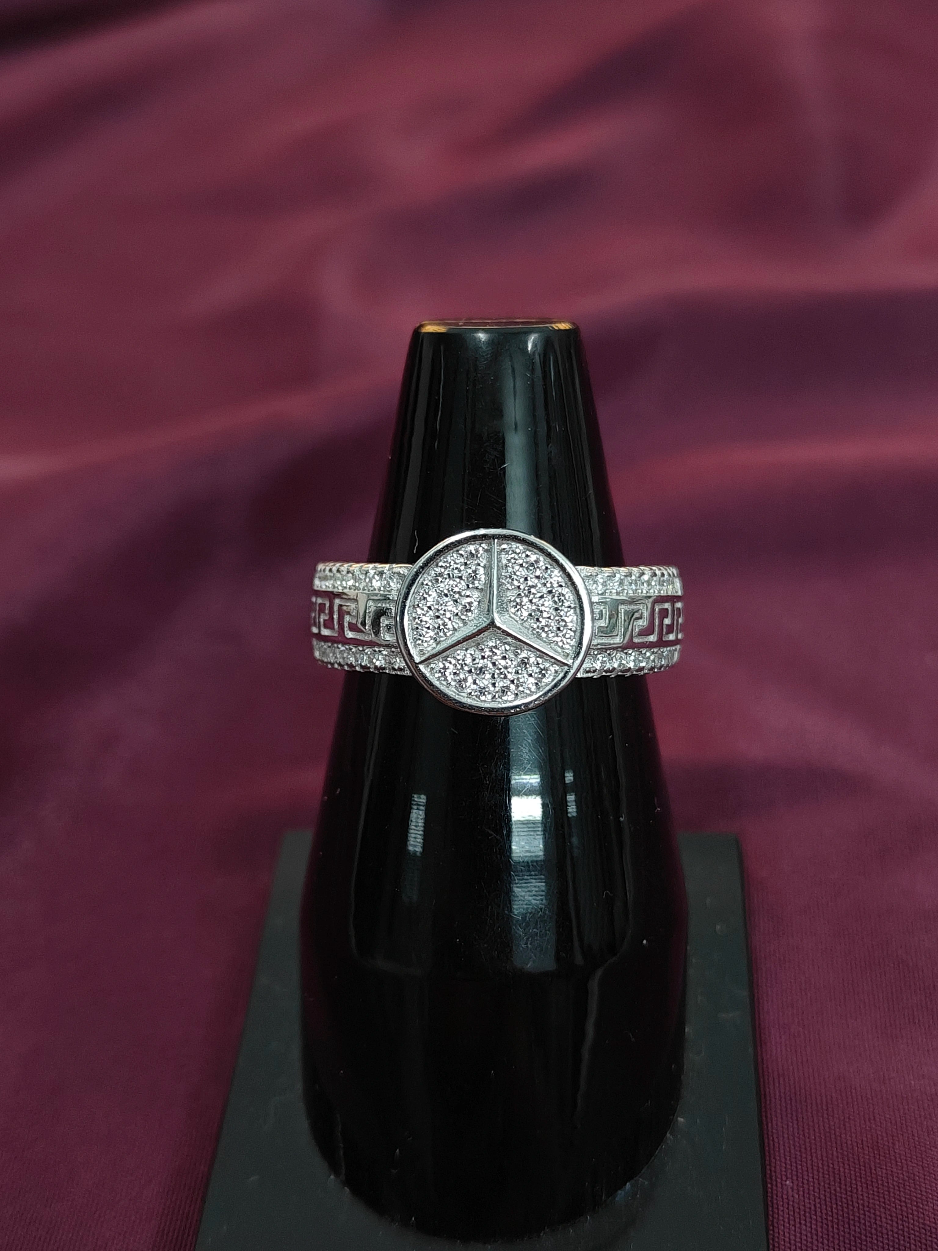 Black perfume bottle with a decorative silver band on a purple fabric background