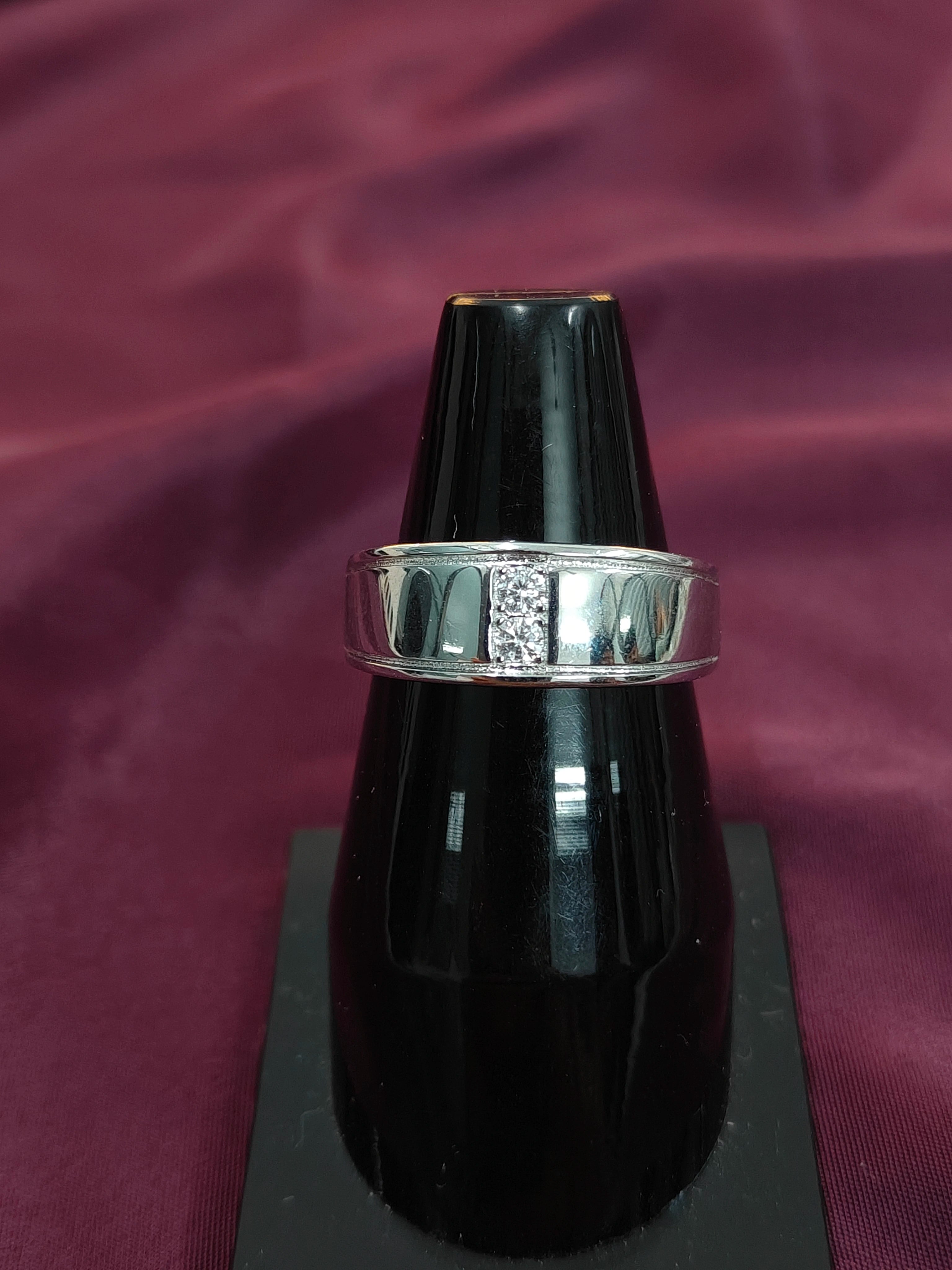 Black lip gloss with silver band on a purple fabric background